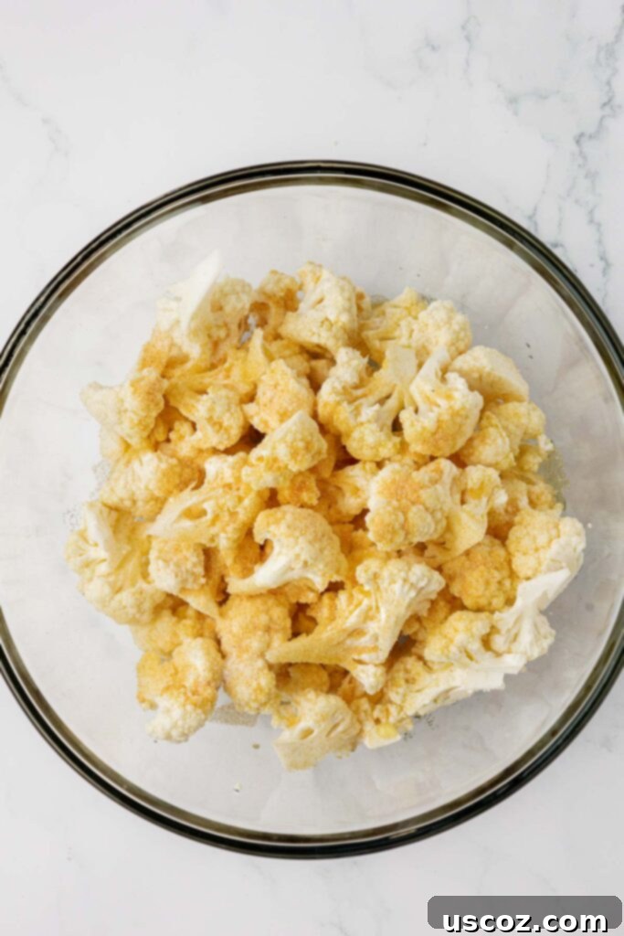 Golden Cheesy Roasted Cauliflower 10 adding the spices to the cauliflower florets in a mixing bowl