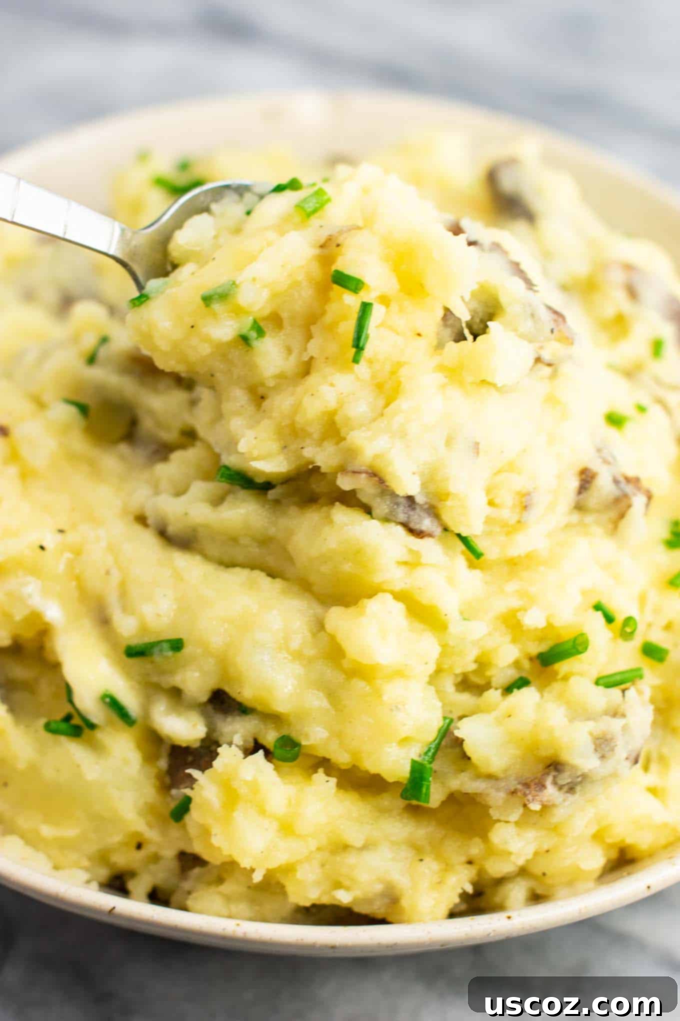 Creamy Vegan Mashed Potatoes 8 A spoon digging into a bowl of fluffy vegan mashed potatoes, showing the creamy texture and depth.