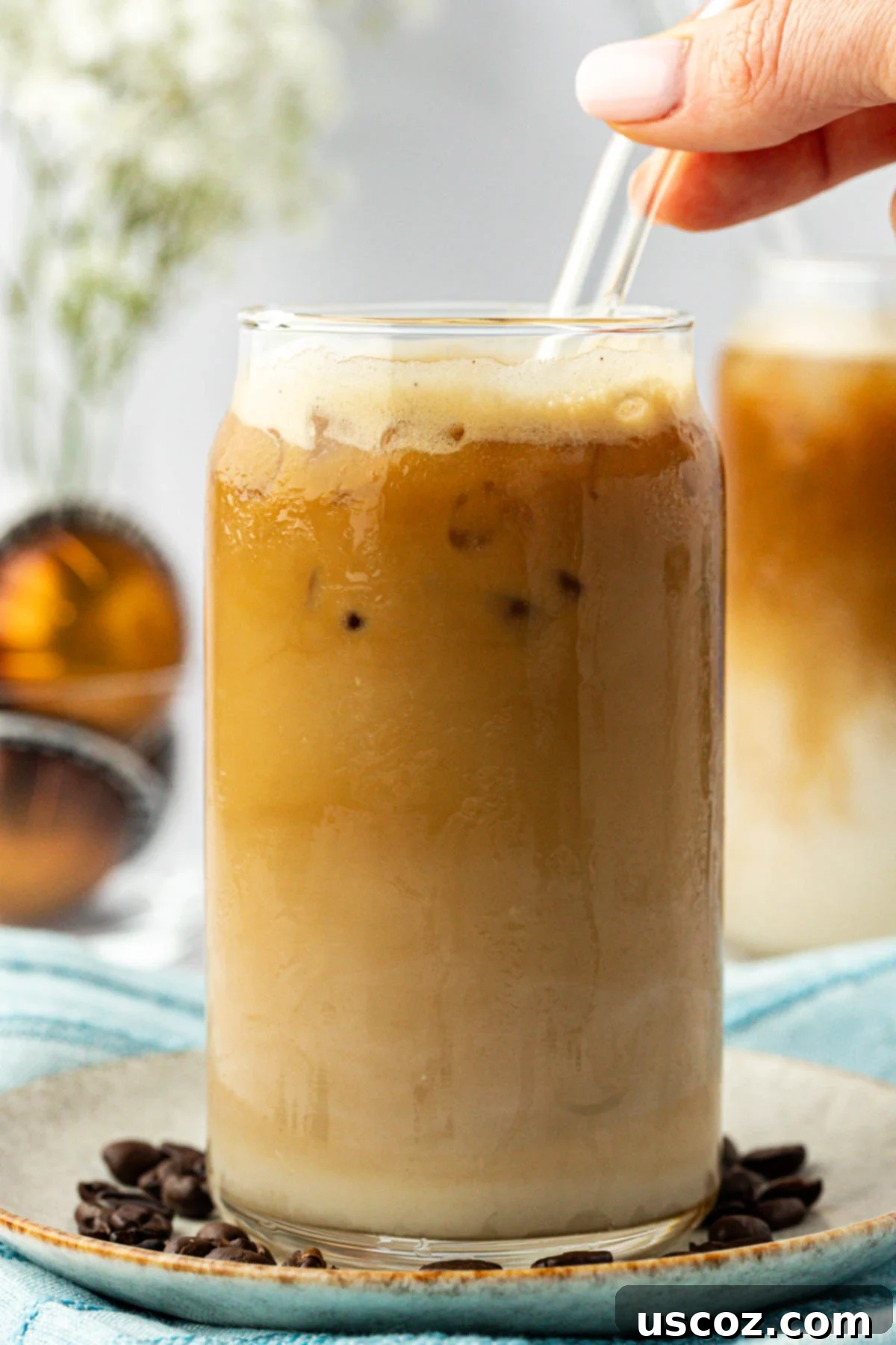 Silky Cold Espresso 11 A refreshing iced latte in a clear glass with a striped straw, beautifully presented with a subtle swirl of espresso and milk, inviting a satisfying sip.
