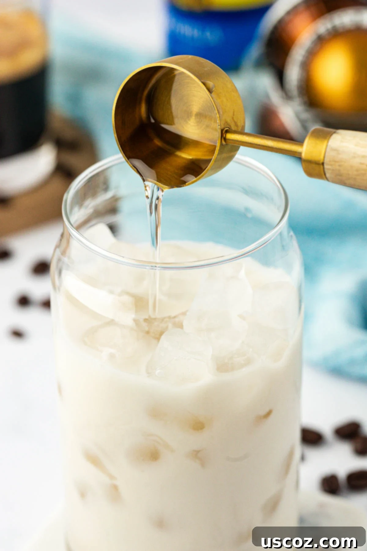 Silky Cold Espresso 5 A stream of rich, amber vanilla coffee syrup being poured into a glass filled with ice and milk, creating the sweet foundation for an iced latte.