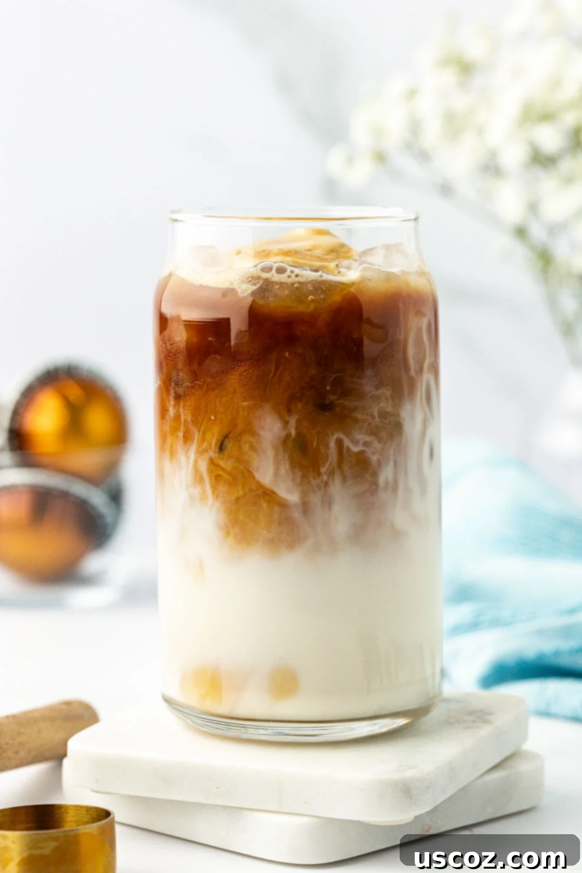 Silky Cold Espresso 8 A close-up of a perfectly crafted iced latte in a clear glass, showing the creamy milk and dark espresso swirling together, topped with a few ice cubes.