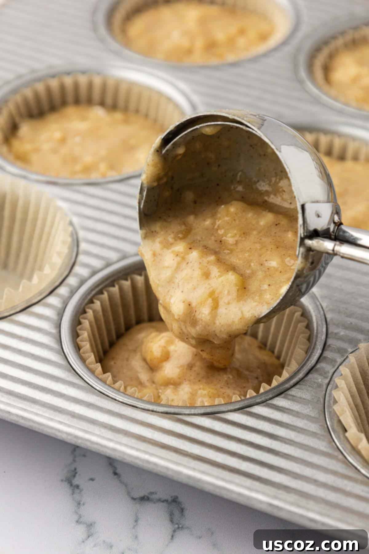 Deliciously Healthy Banana Muffins 11 pouring batter into a muffin tin