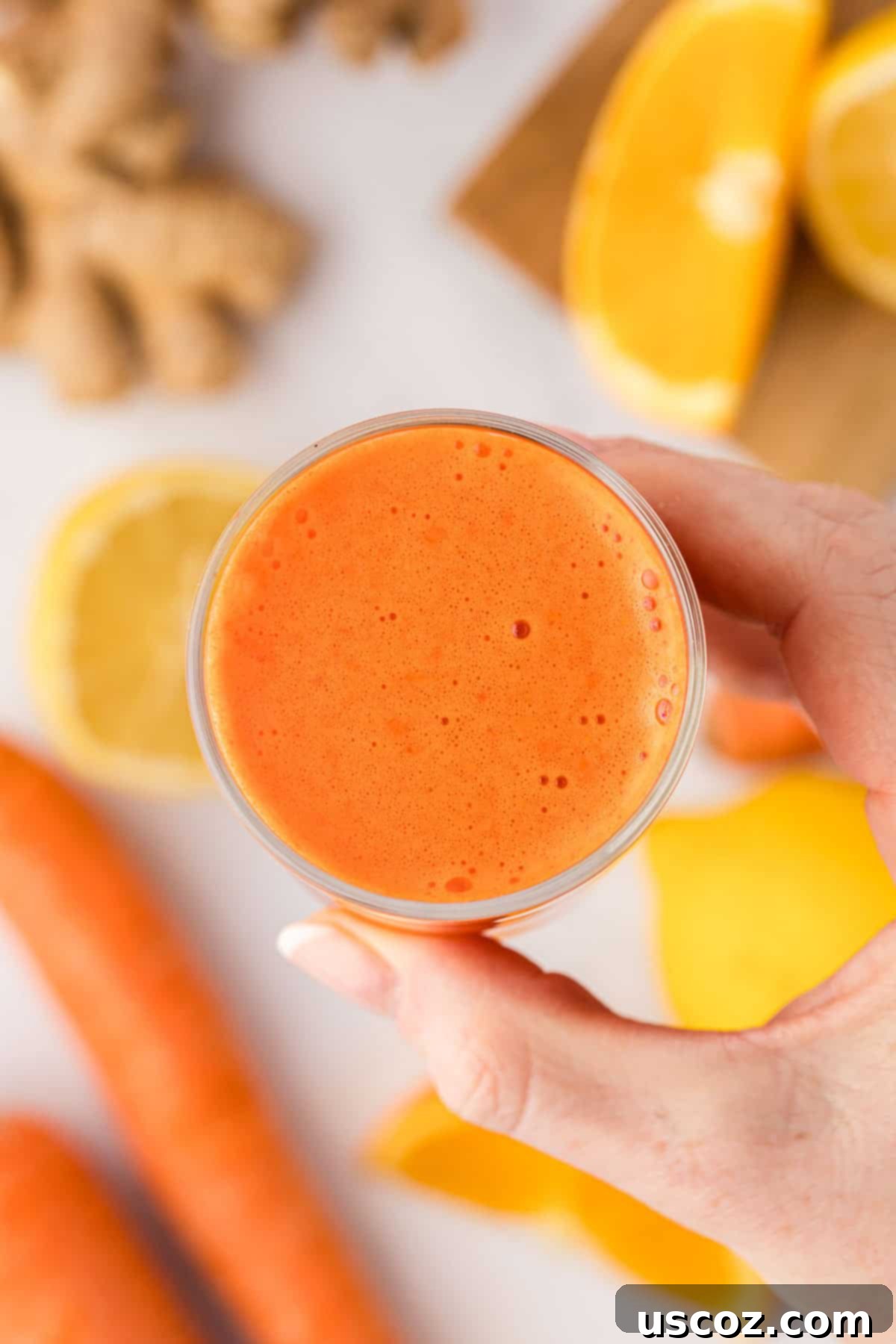 Golden Glow Juice 9 hand holding a glass of carrot orange juice
