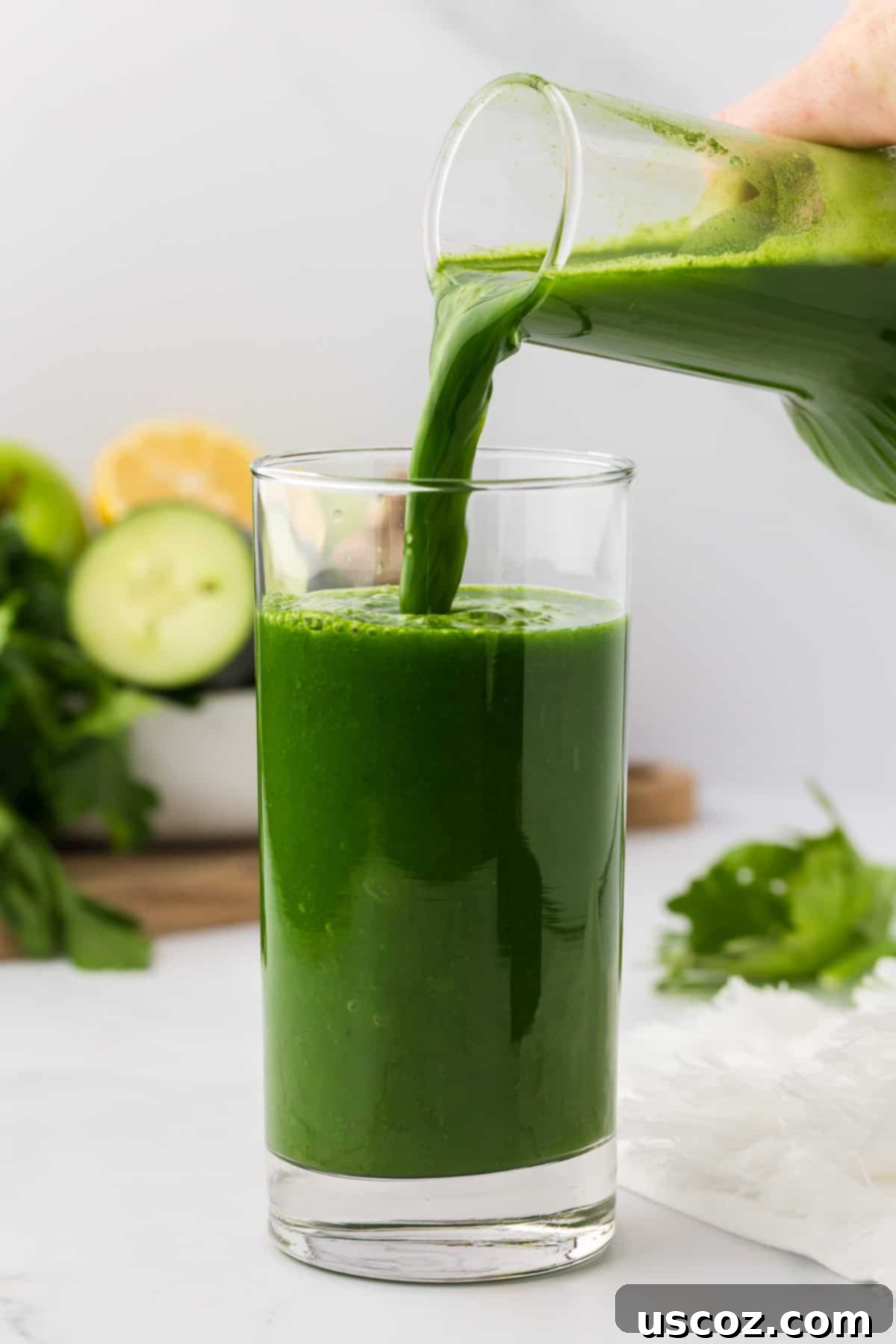 Vital Veggie Boost 6 Hand pouring vibrant green vegetable juice from a pitcher into a glass.