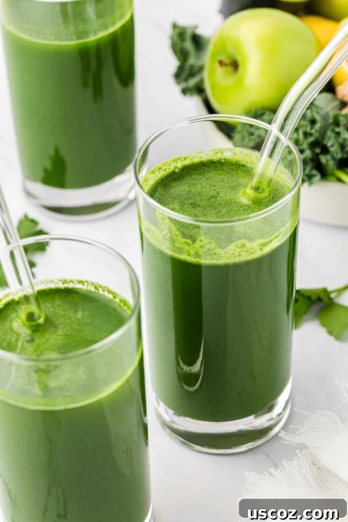 Vital Veggie Boost 8 A tall glass of vibrant green vegetable juice with a reusable straw on a bright background.
