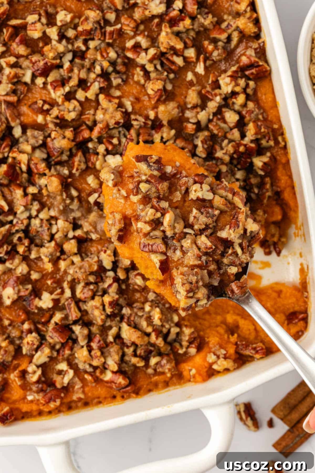 Golden Sweet Potato & Pecan Delight 13 A close-up of a serving spoon presenting a perfect scoop of sweet potato casserole, revealing its creamy filling and delightful pecan topping.