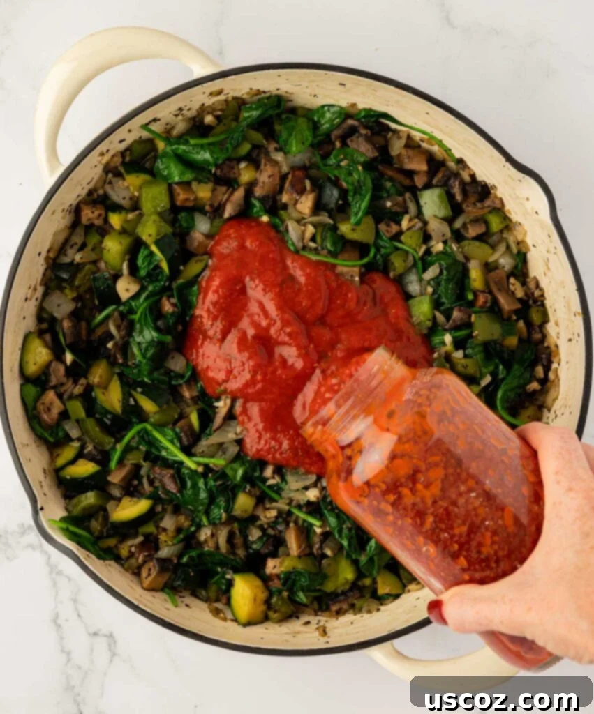 pouring pasta sauce into the vegetables