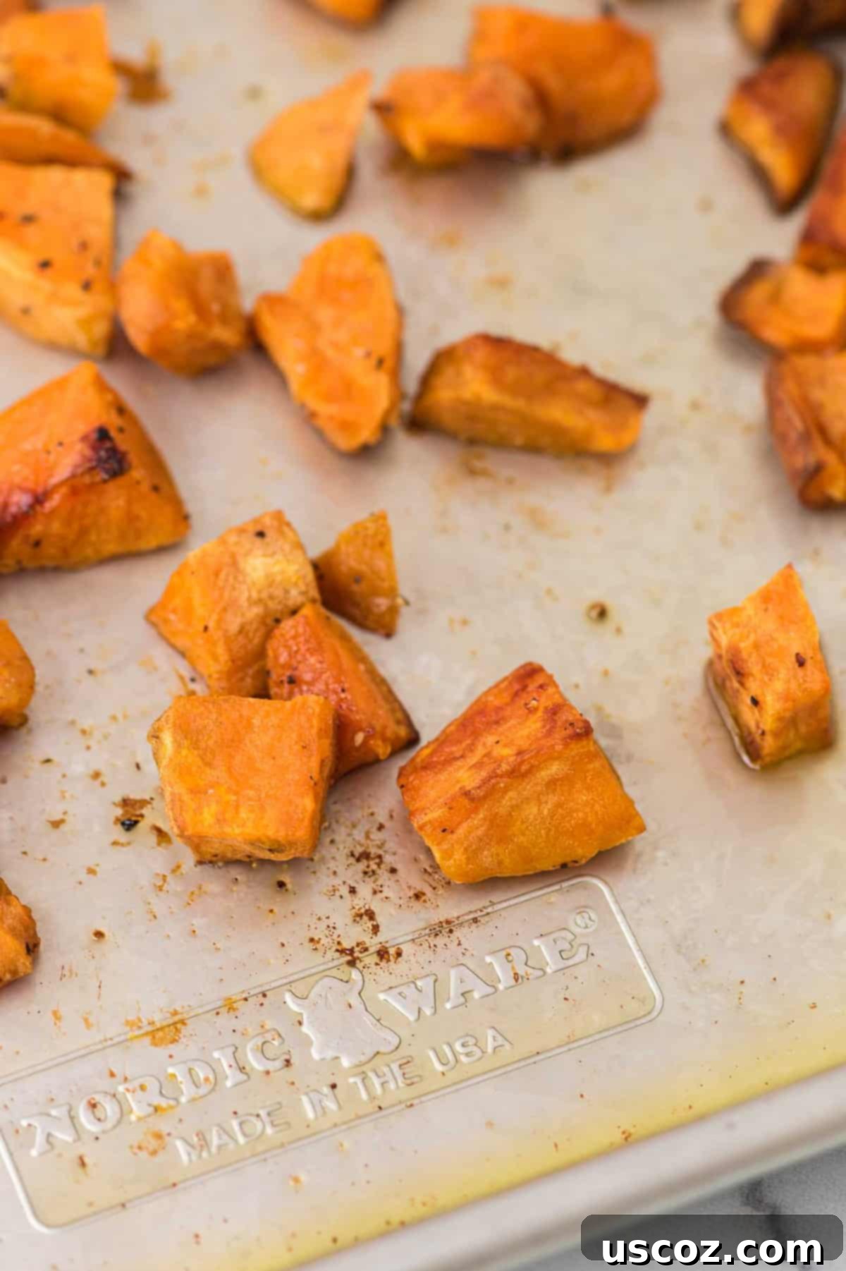 Golden Roasted Sweet Potato Bites 8 A bowl of freshly roasted sweet potatoes, garnished with herbs, showcasing their vibrant color and inviting texture.