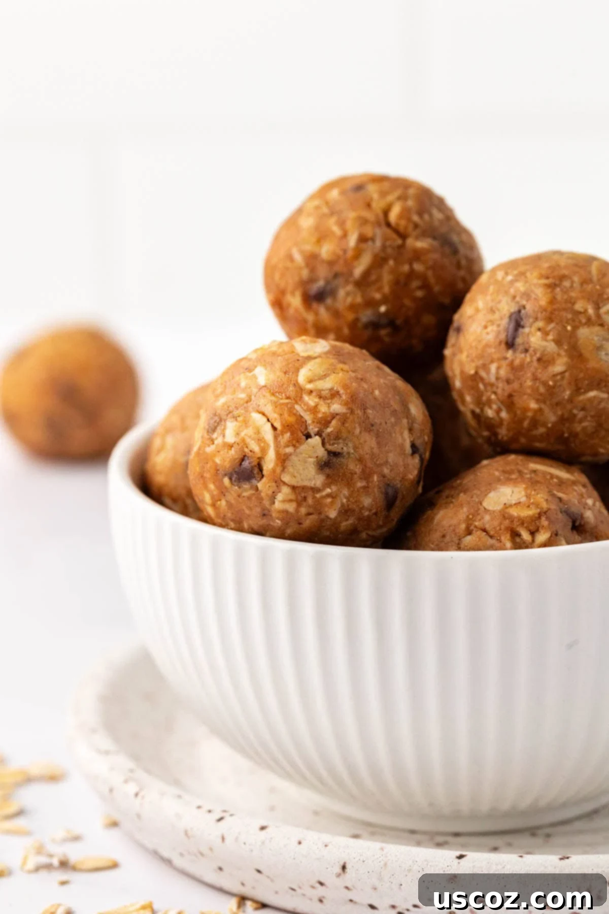 Oat Cookie Power Bites 3 A close-up of a stack of oatmeal cookie energy balls, showcasing their texture and ingredients like oats and chocolate chips.