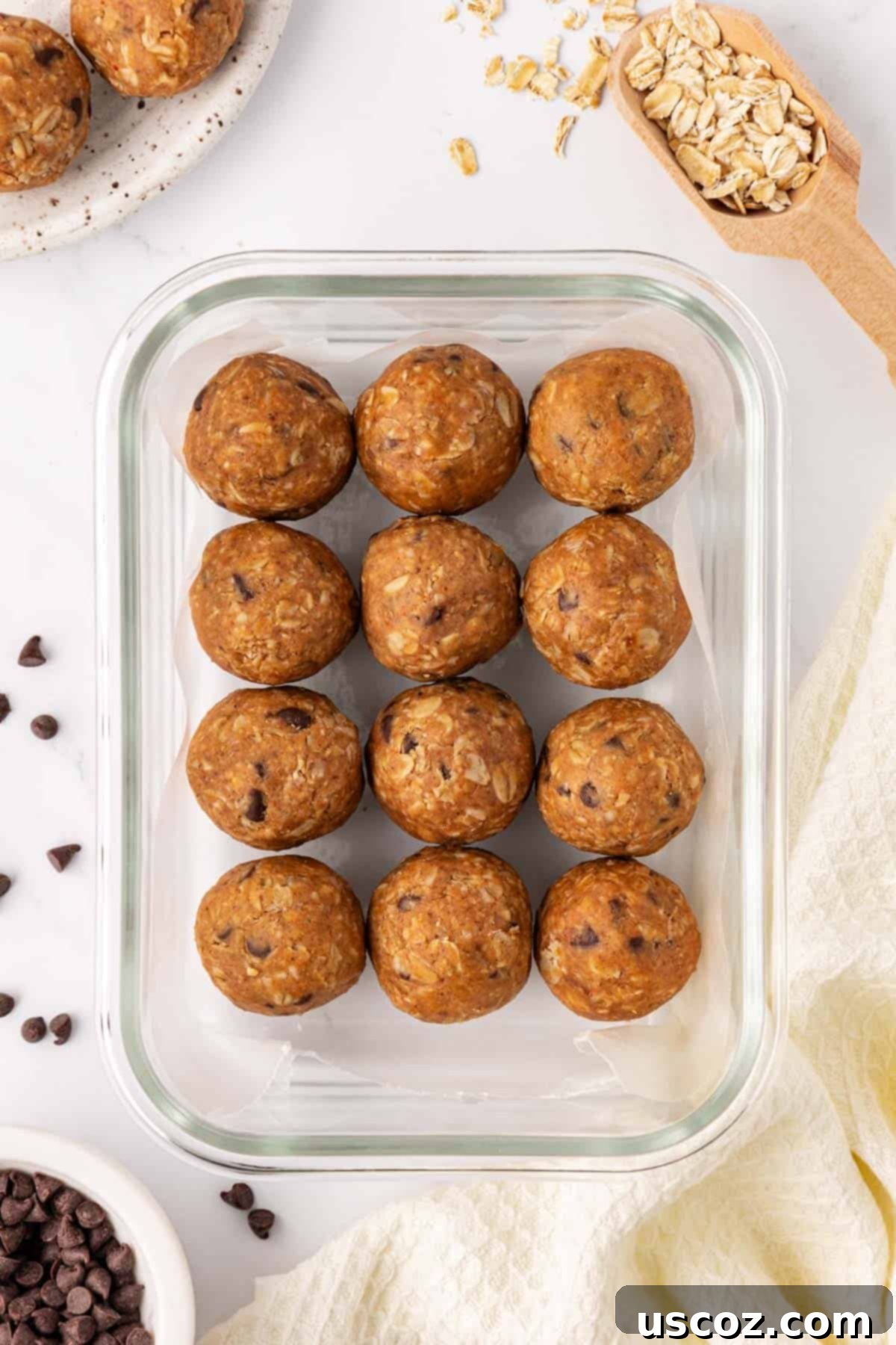 Oat Cookie Power Bites 8 A few delicious oatmeal cookie energy balls stacked on a small wooden board, with oats visible in the background.