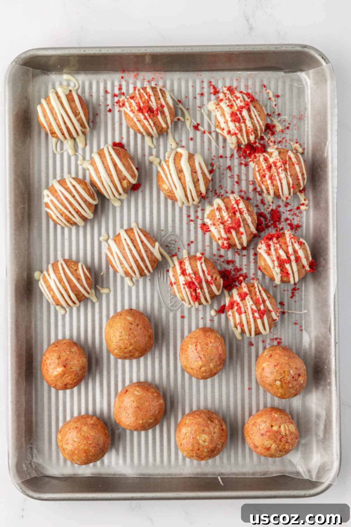 Strawberry Cream Energy Bites 9 strawberries and cream energy bites on a baking sheet, freshly drizzled