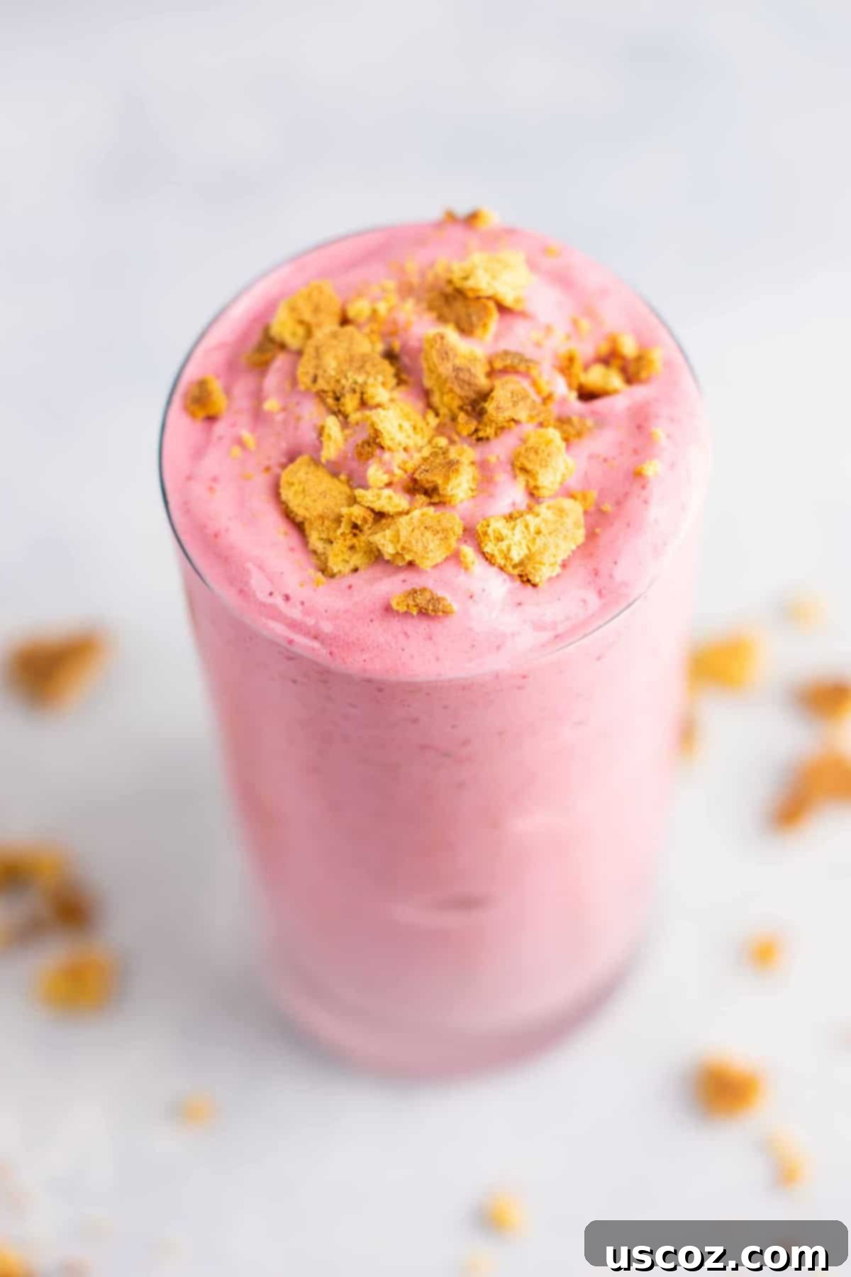 strawberry cheesecake smoothie in a glass with crushed graham cracker on top