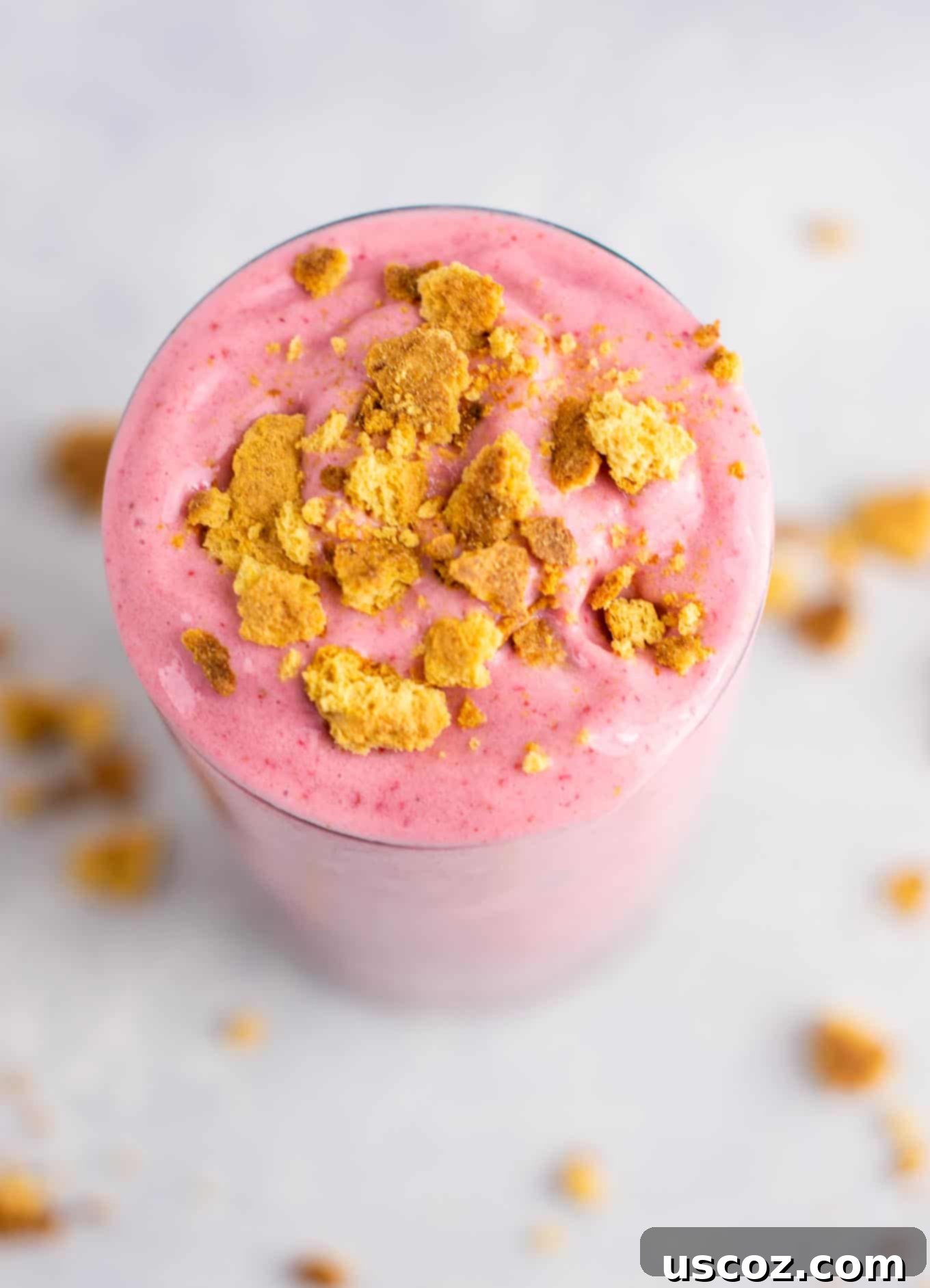 strawberry cheesecake smoothie in a glass with crushed graham cracker on top