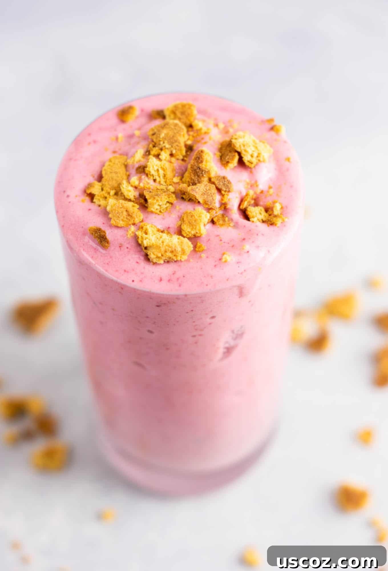 strawberry cheesecake smoothie in a glass with crushed graham cracker on top