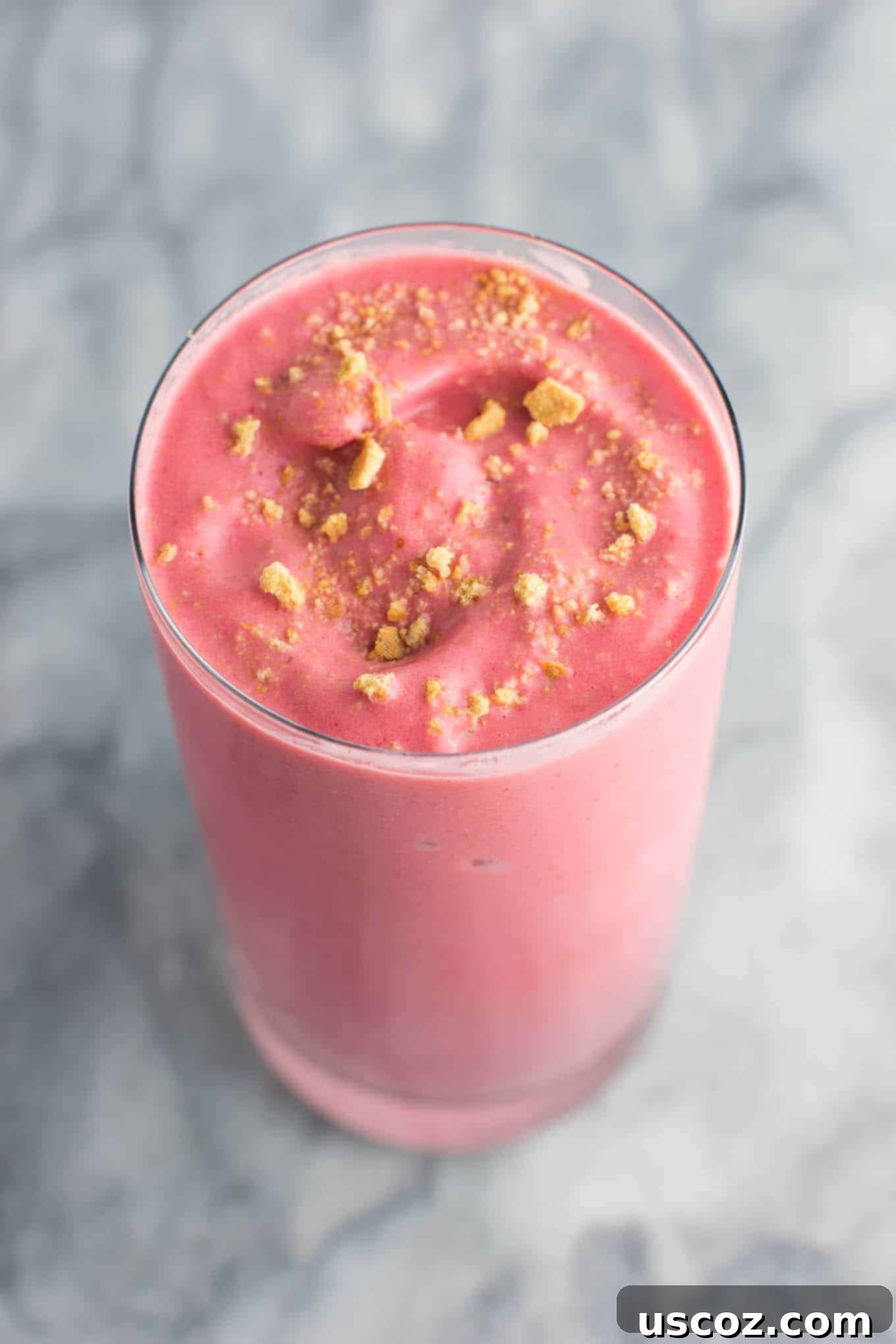 strawberry cheesecake smoothie in a glass with crushed graham cracker on top