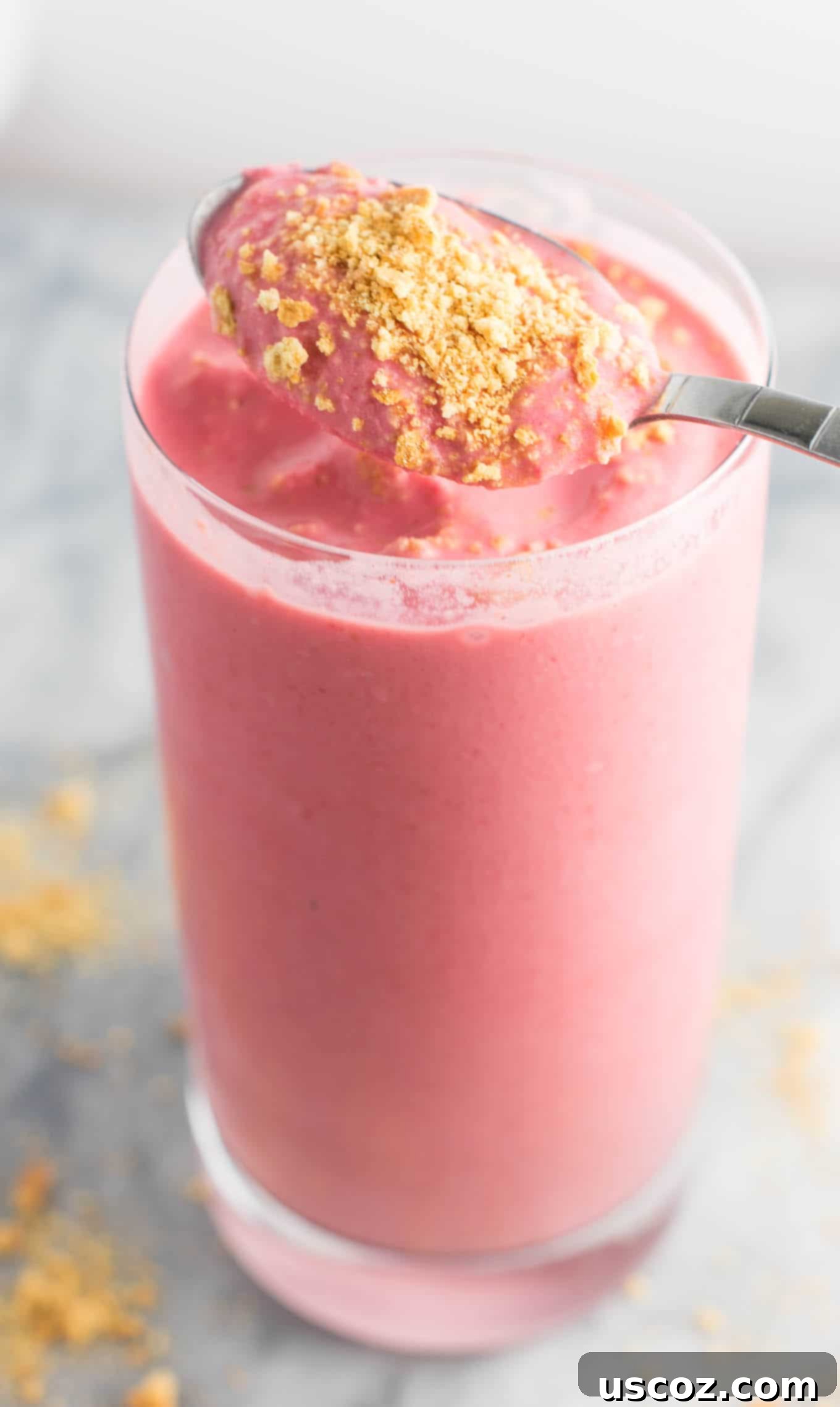 a spoon taking a scoop of smoothie from the glass to show the thick texture