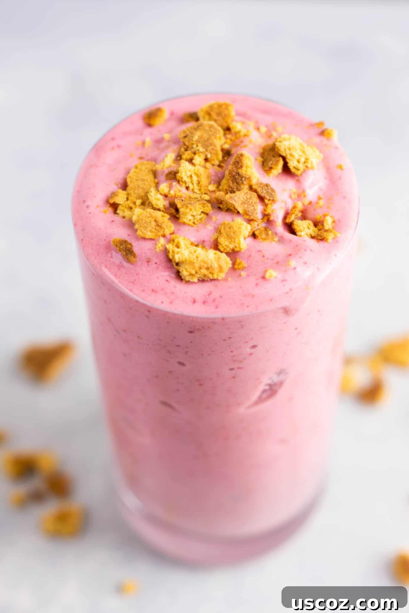 strawberry cheesecake smoothie in a glass with crushed graham cracker on top