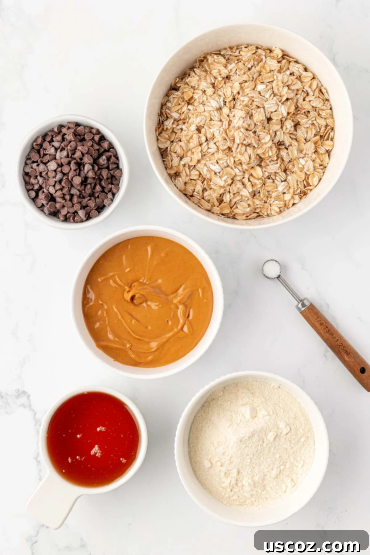Power-Packed Protein Granola Bars 4 All the ingredients laid out on a table, ready to make protein granola bars: peanut butter, honey, protein powder, rolled oats, salt, and mini chocolate chips.