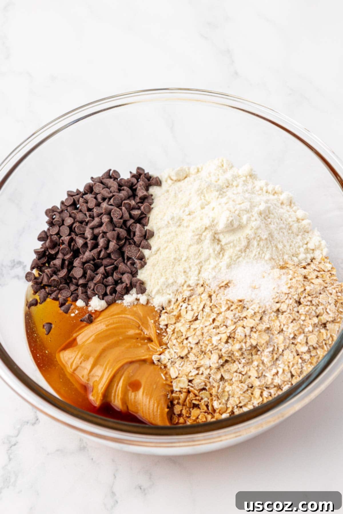 Monster Cookie Protein Bars 5 Mixing bowl with peanut butter, honey, oats, protein powder, and other ingredients for protein bars before mixing