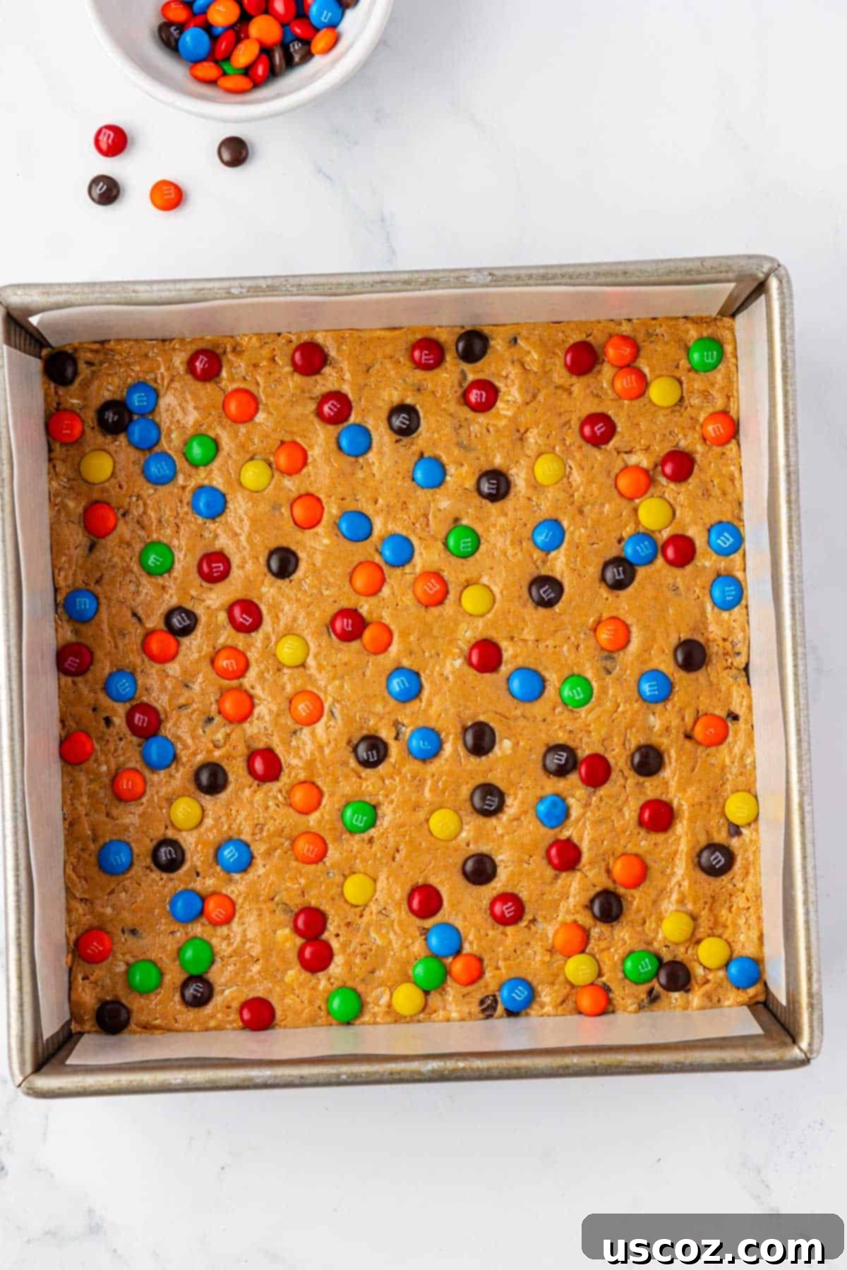 Monster Cookie Protein Bars 9 Side view of the monster cookie protein bar batter pressed into a pan with M&Ms, showing its thick texture