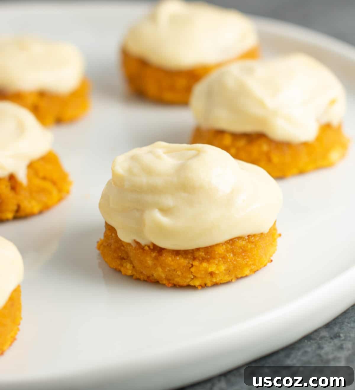 Pumpkin Spice Gluten Free Cookie Delights 2 gluten free pumpkin cookies with cream cheese frosting on a plate