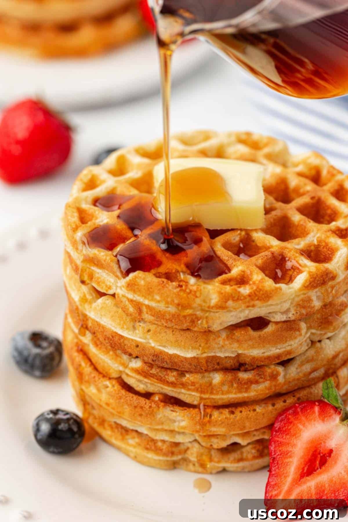 A pair of perfectly golden Greek yogurt waffles on a white plate, ready to be topped.