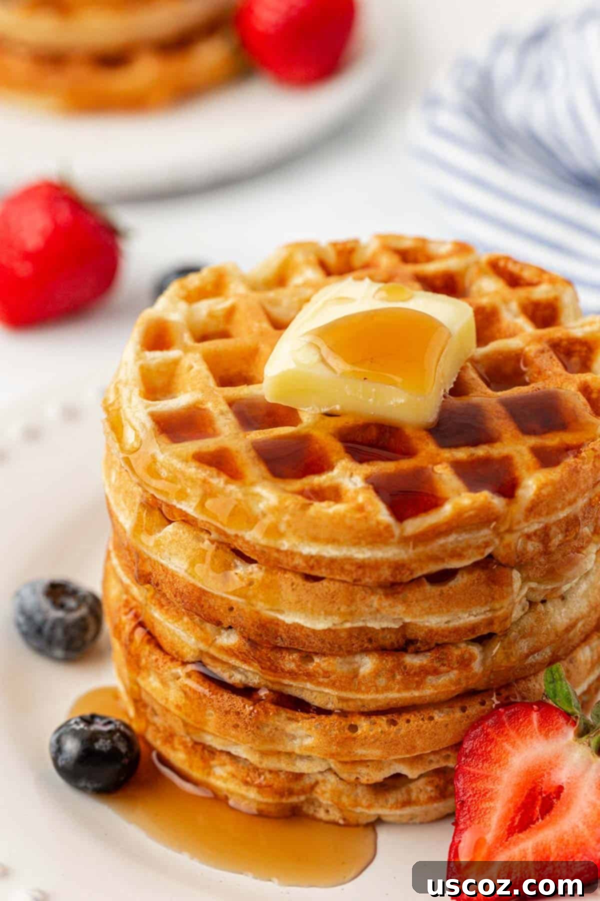 Three perfectly golden Greek yogurt waffles stacked on a white plate, ready to be enjoyed.