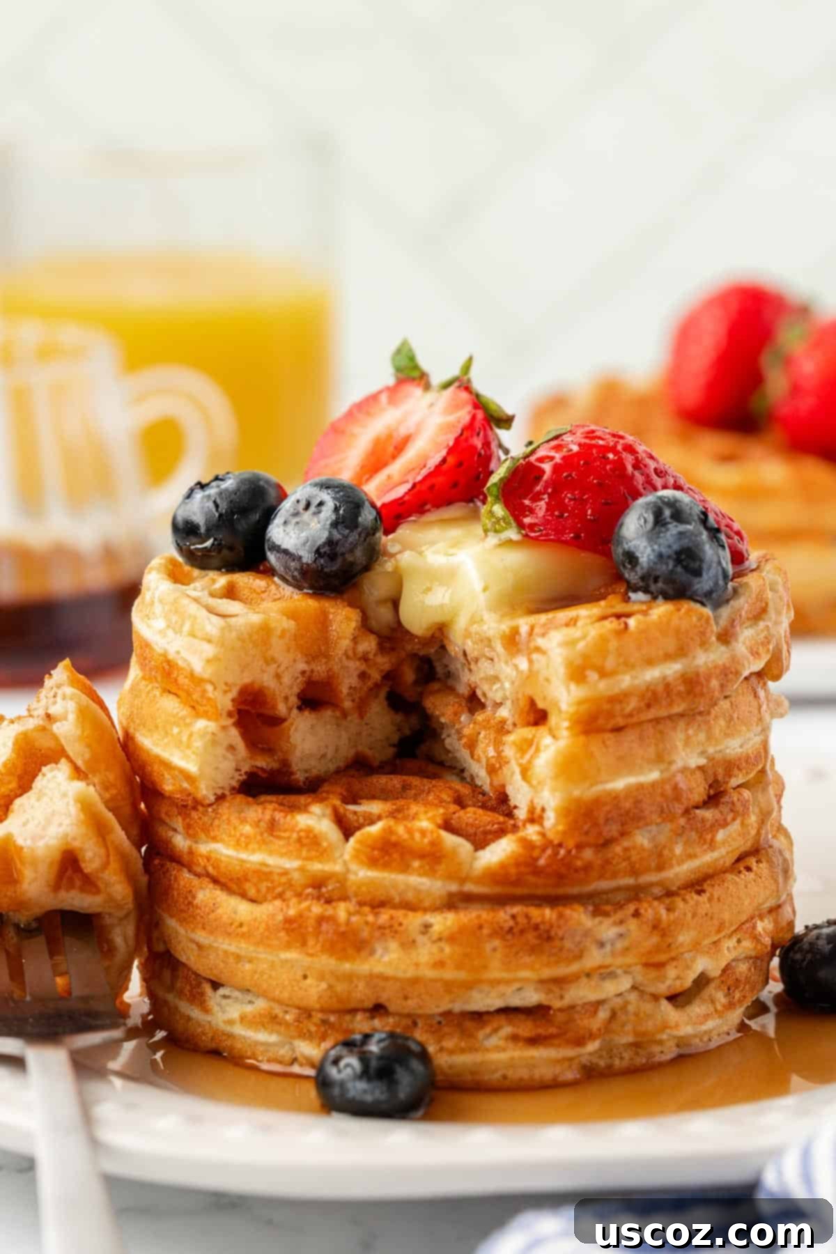 Stack of Greek yogurt waffles garnished with fresh berries, maple syrup, and a pat of butter, showcasing their delicious appeal.