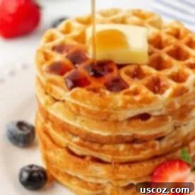 A perfectly cooked Greek yogurt waffle, round and golden-brown, ready to be served.