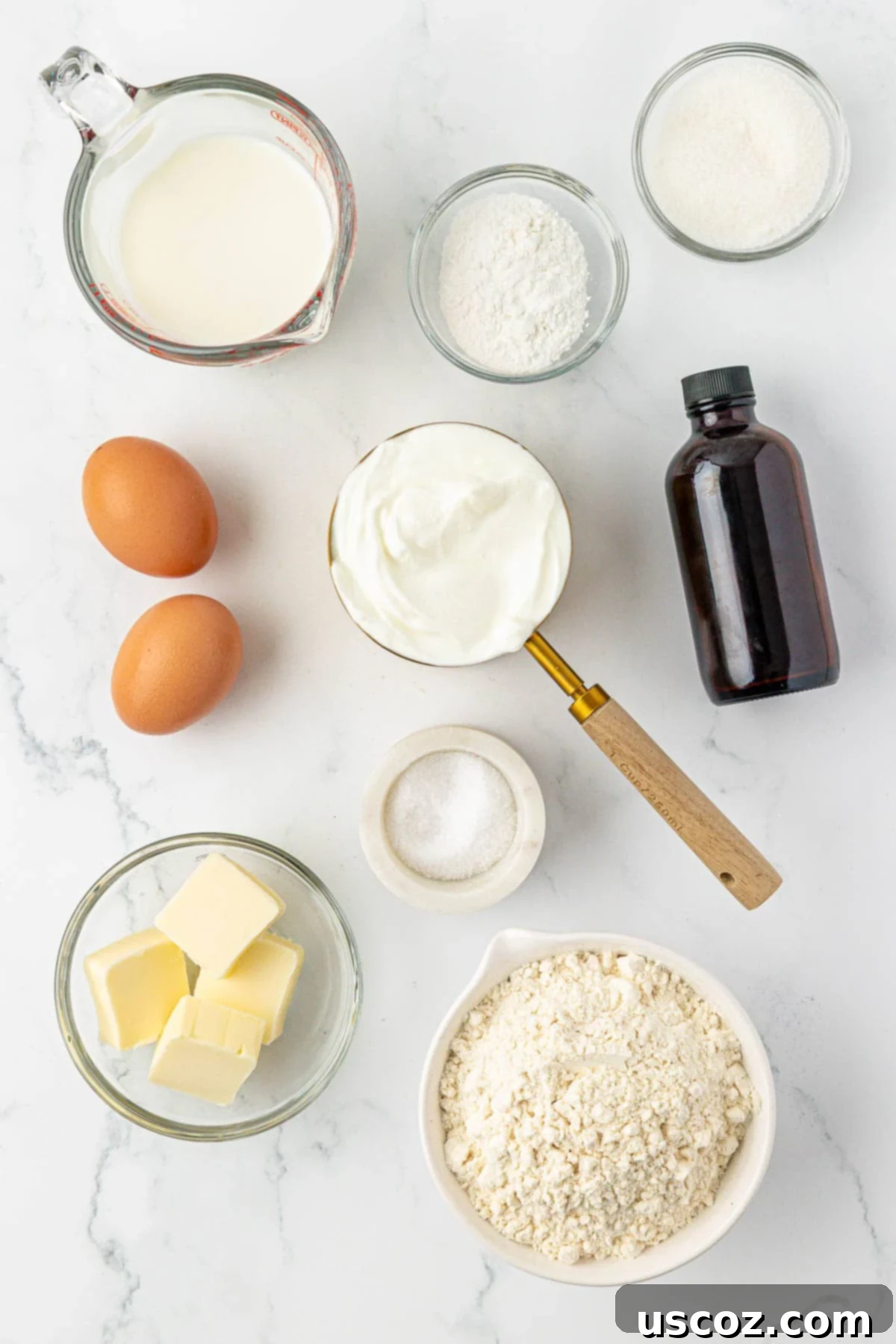 Assortment of fresh ingredients laid out: flour, baking powder, sugar, Greek yogurt, milk, melted butter, eggs, vanilla extract, and salt, ready for making waffles.