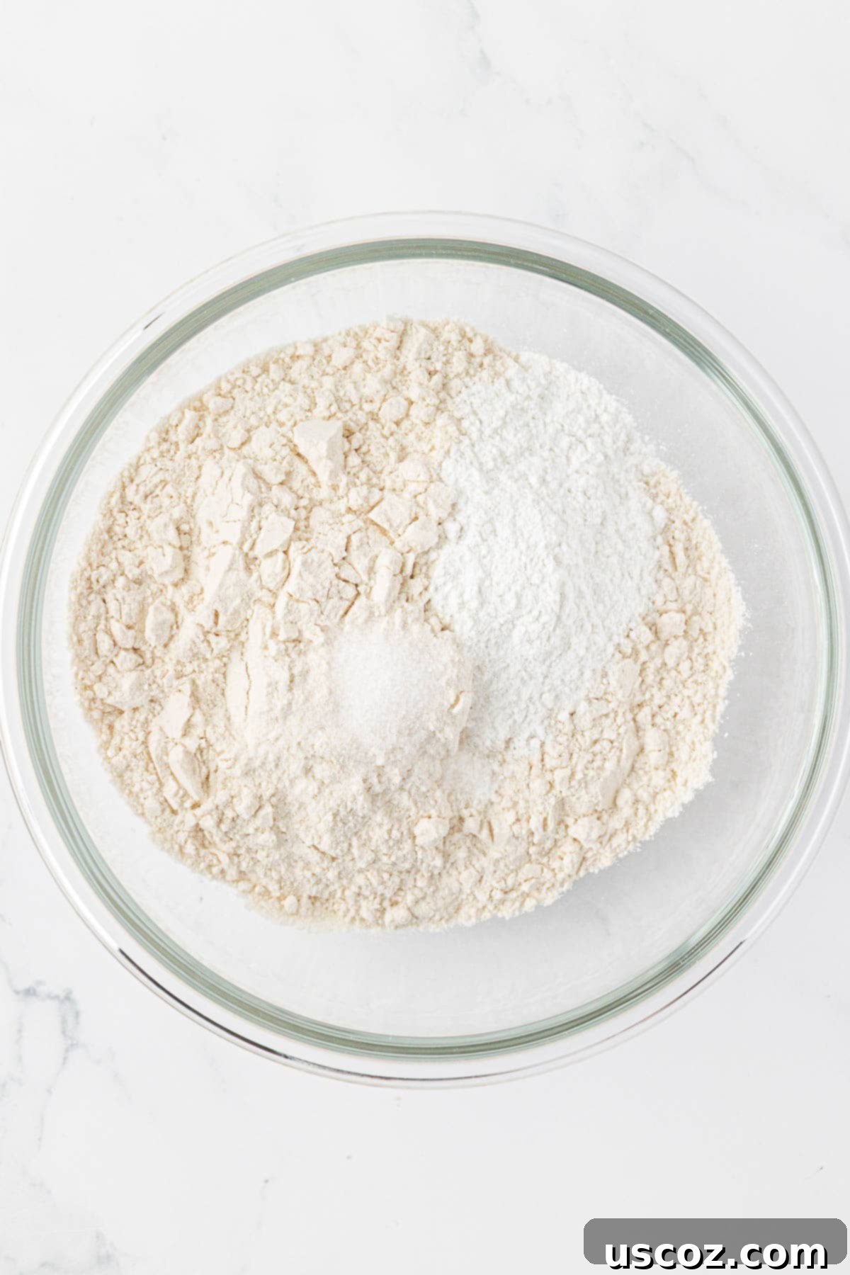 A bowl filled with dry ingredients: flour, baking powder, and salt, before whisking.