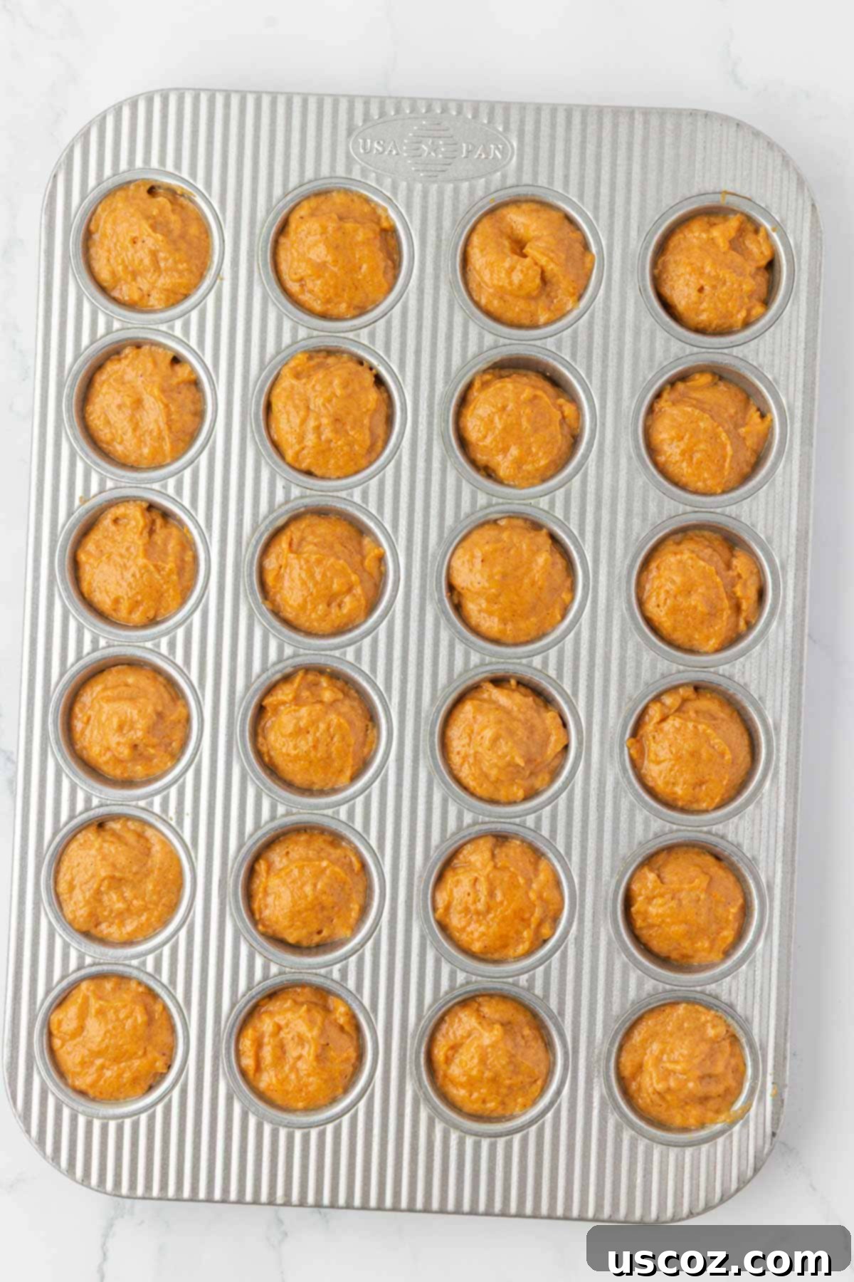 mini muffin tin filled with pumpkin muffin batter