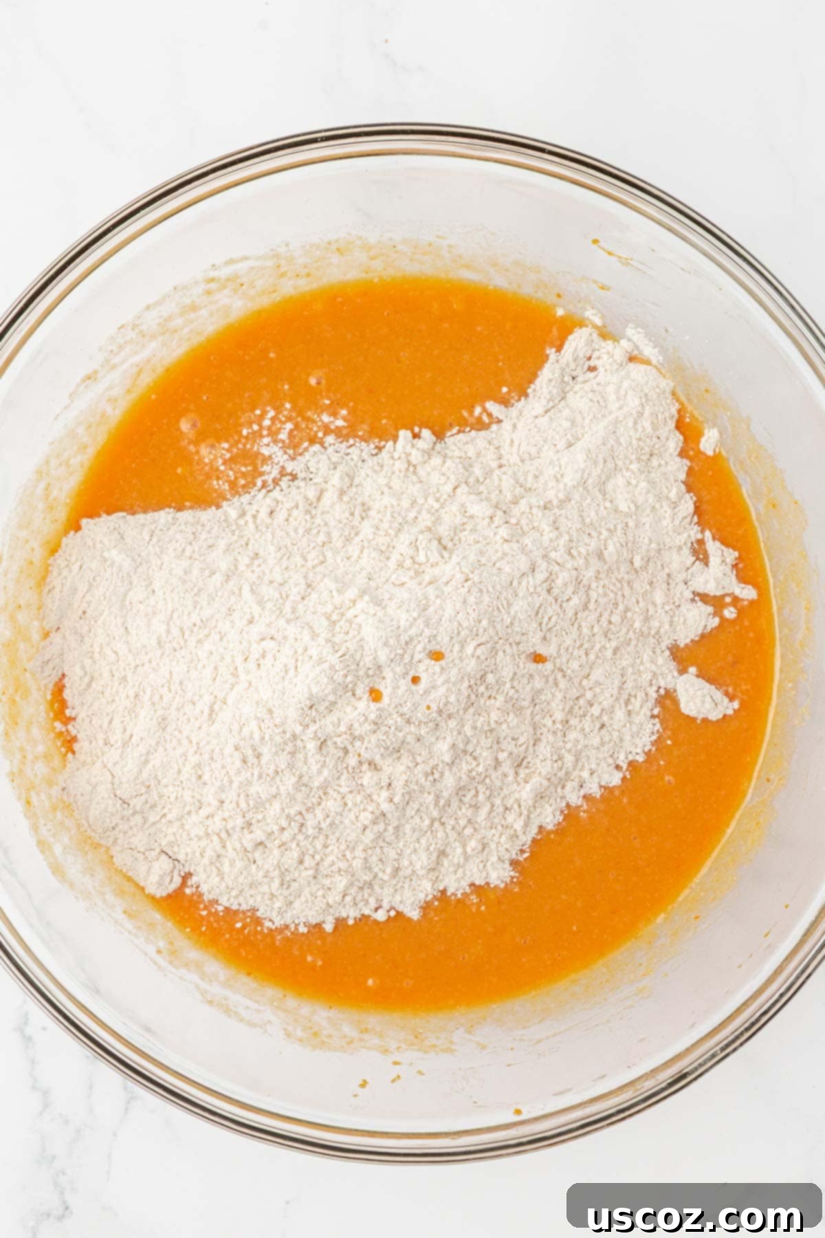 adding dry ingredients to wet for pumpkin muffin batter