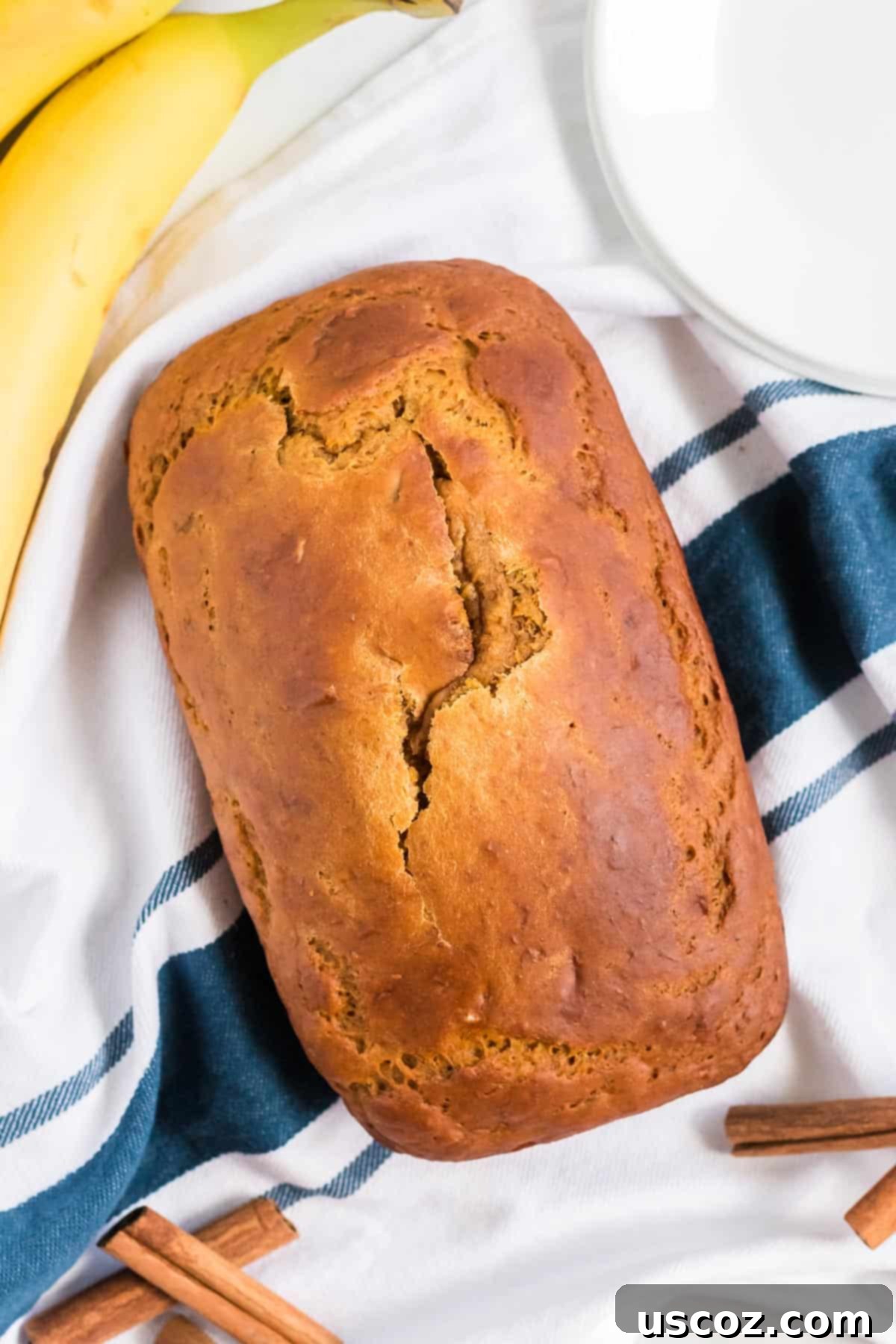 Wholesome Spiced Pumpkin and Banana Bread 12 A warm loaf of pumpkin banana bread resting on a patterned kitchen towel.