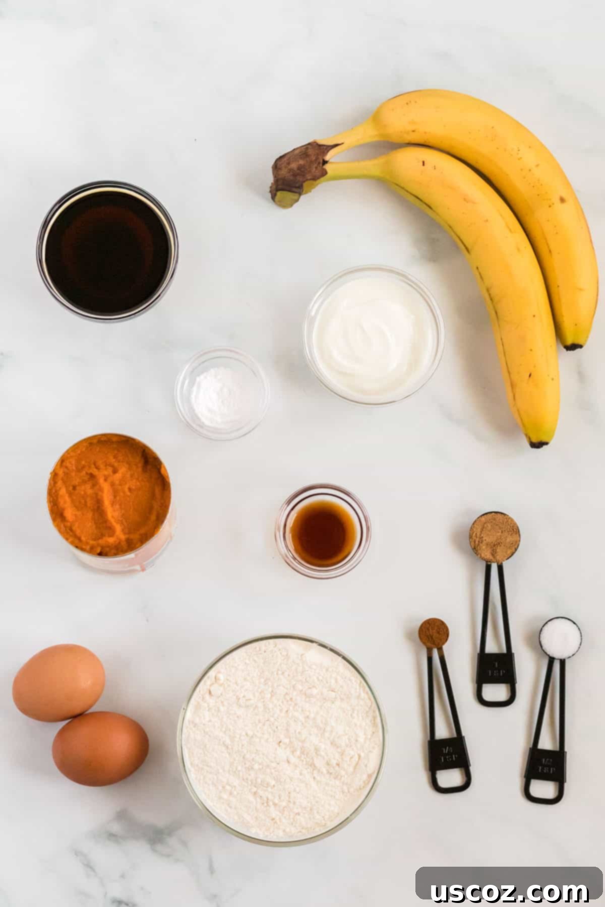 Wholesome Spiced Pumpkin and Banana Bread 3 A flat lay image displaying all the raw ingredients needed to make healthy pumpkin banana bread: yogurt, maple syrup, bananas, pumpkin puree, eggs, spices, and flour.