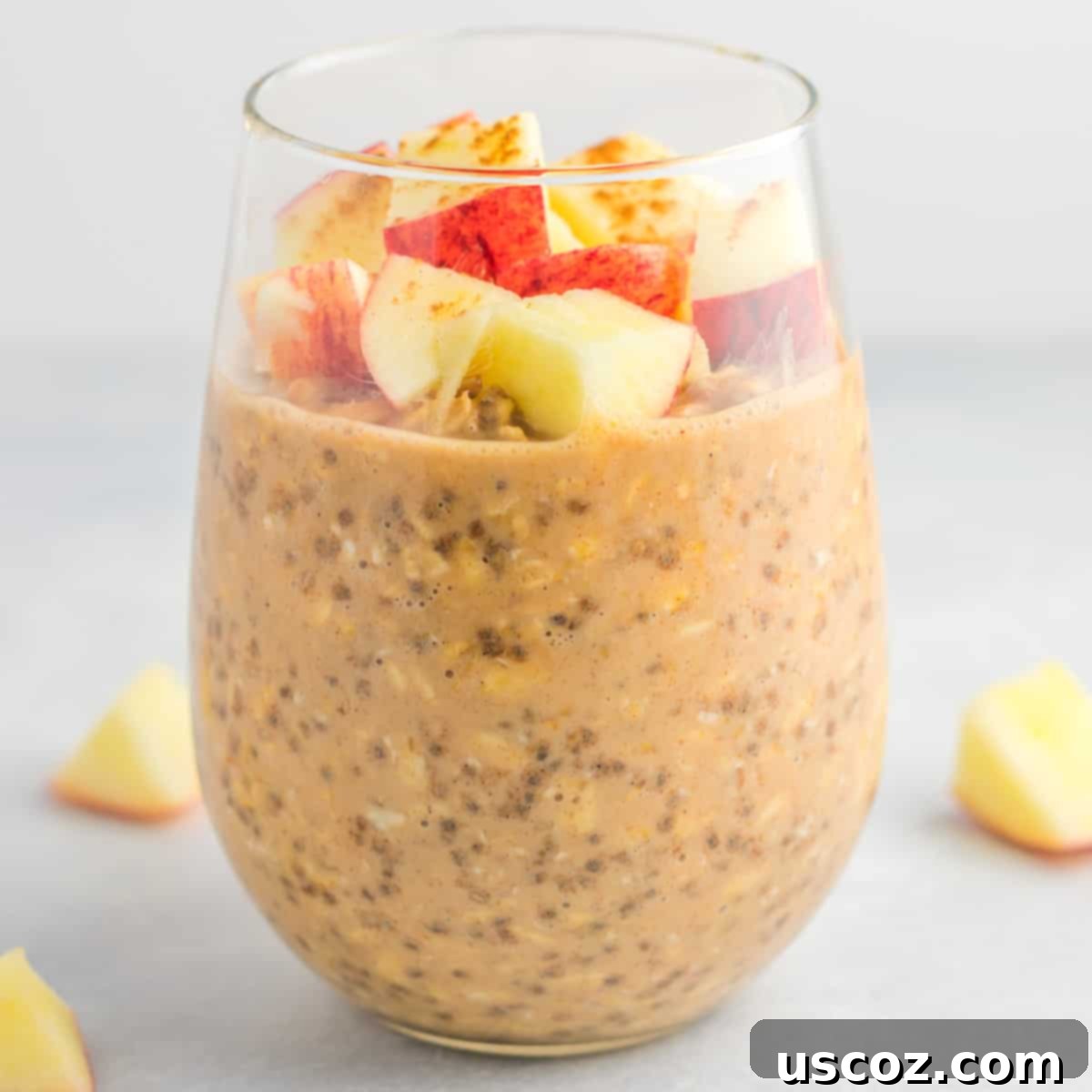 Apple Cinnamon Overnight Oats 4 Individual ingredients for apple cinnamon overnight oats laid out: rolled oats, almond milk, chia seeds, vanilla, cinnamon, maple syrup, peanut butter, and a whole apple.