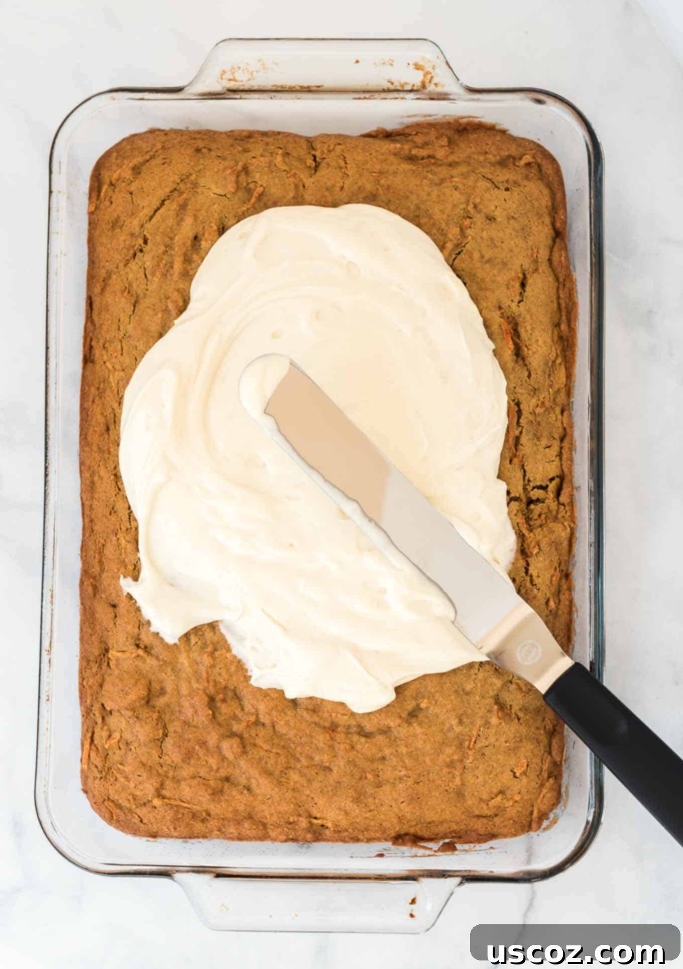Gluten-Free Carrot Cake Perfection 4 Spreading rich, creamy frosting onto a baked gluten-free carrot cake in a sheet pan, illustrating the simple frosting process.