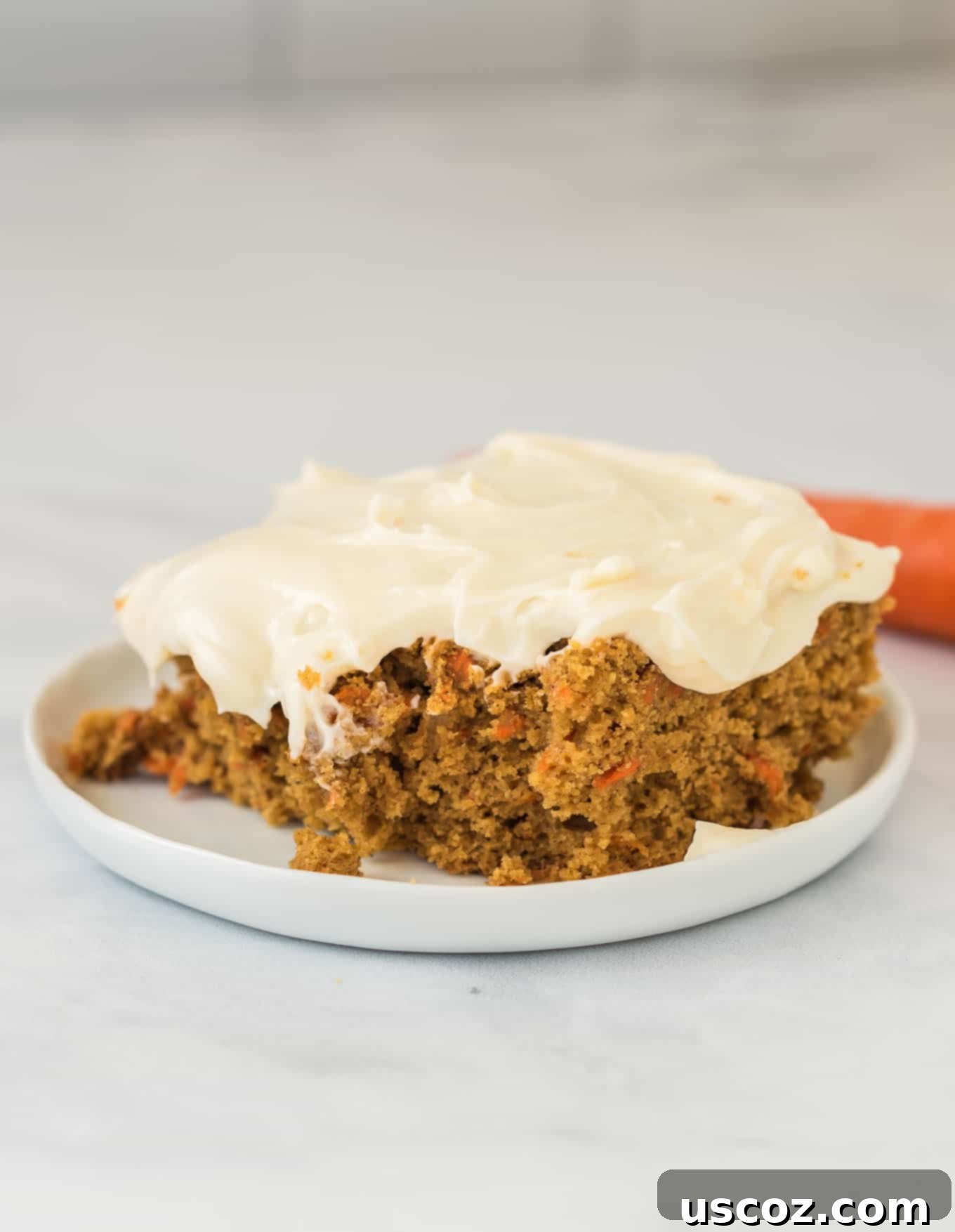 Gluten-Free Carrot Cake Perfection 9 Another appetizing image of a gluten-free carrot cake slice with creamy frosting on a white plate, highlighting its moist interior.