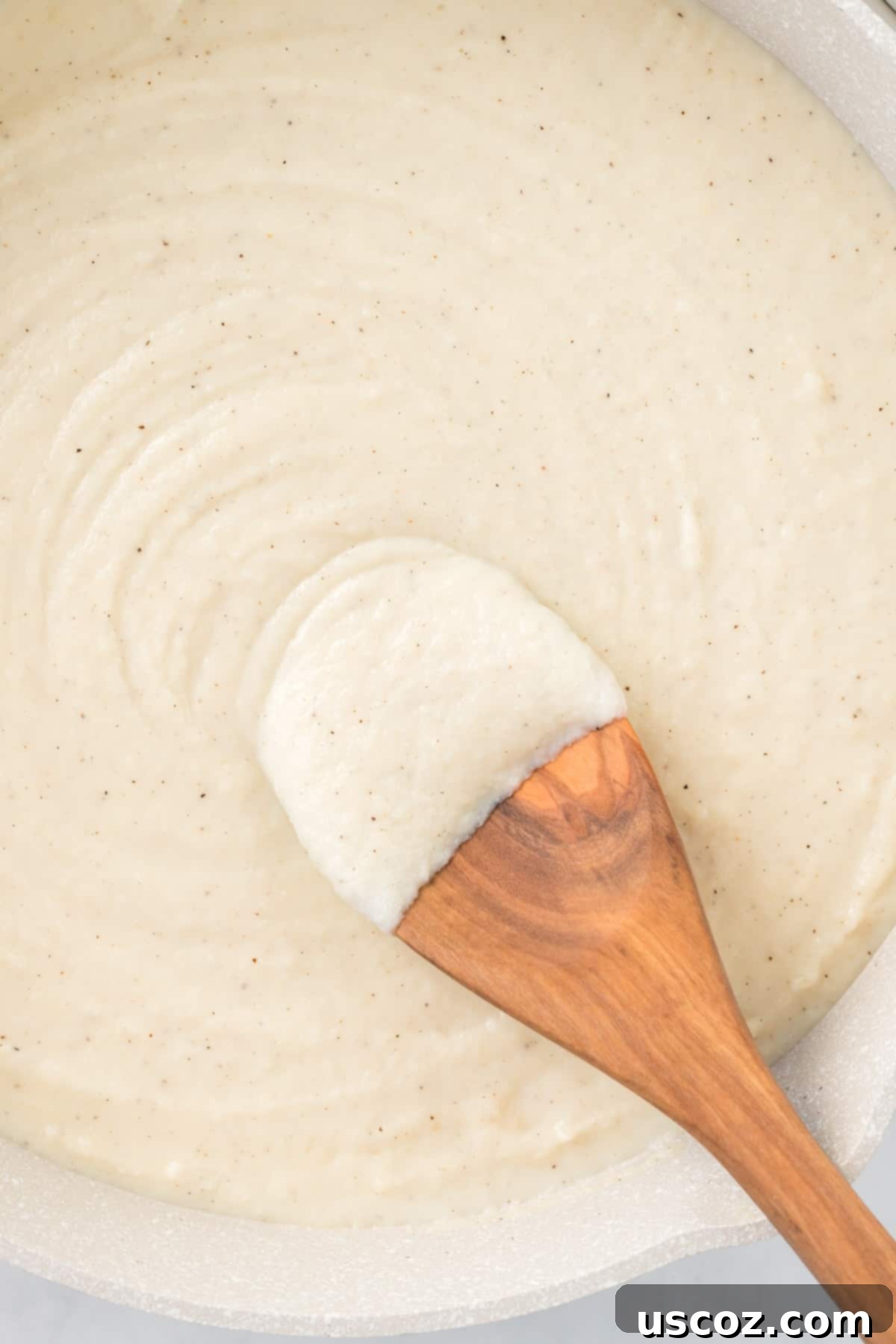 Creamy Cauliflower Alfredo 2 wooden spoon dipped in cauliflower alfredo sauce