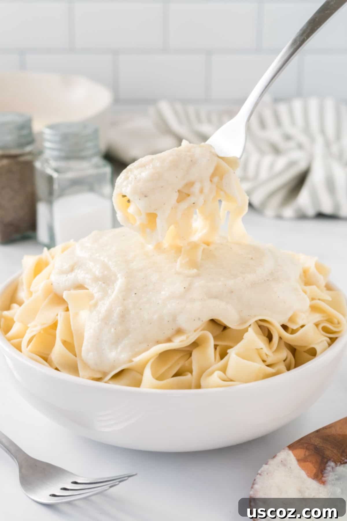 Creamy Cauliflower Alfredo 15 a fork taking a bite of fettuccini with Alfredo sauce