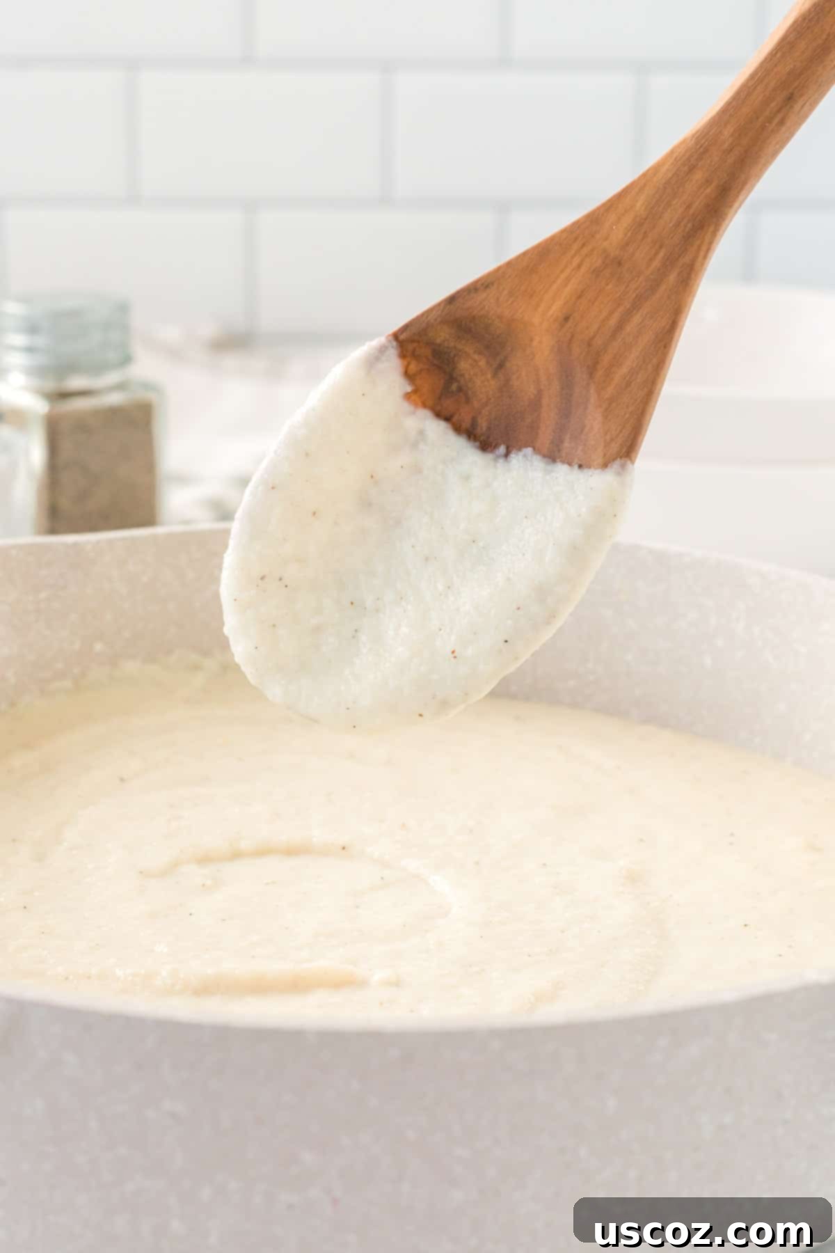 Creamy Cauliflower Alfredo 16 wooden spoon dipped in cauliflower alfredo sauce