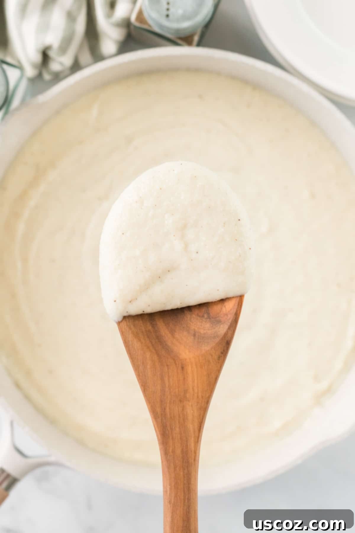Creamy Cauliflower Alfredo 17 wooden spoon dipped in cauliflower alfredo sauce