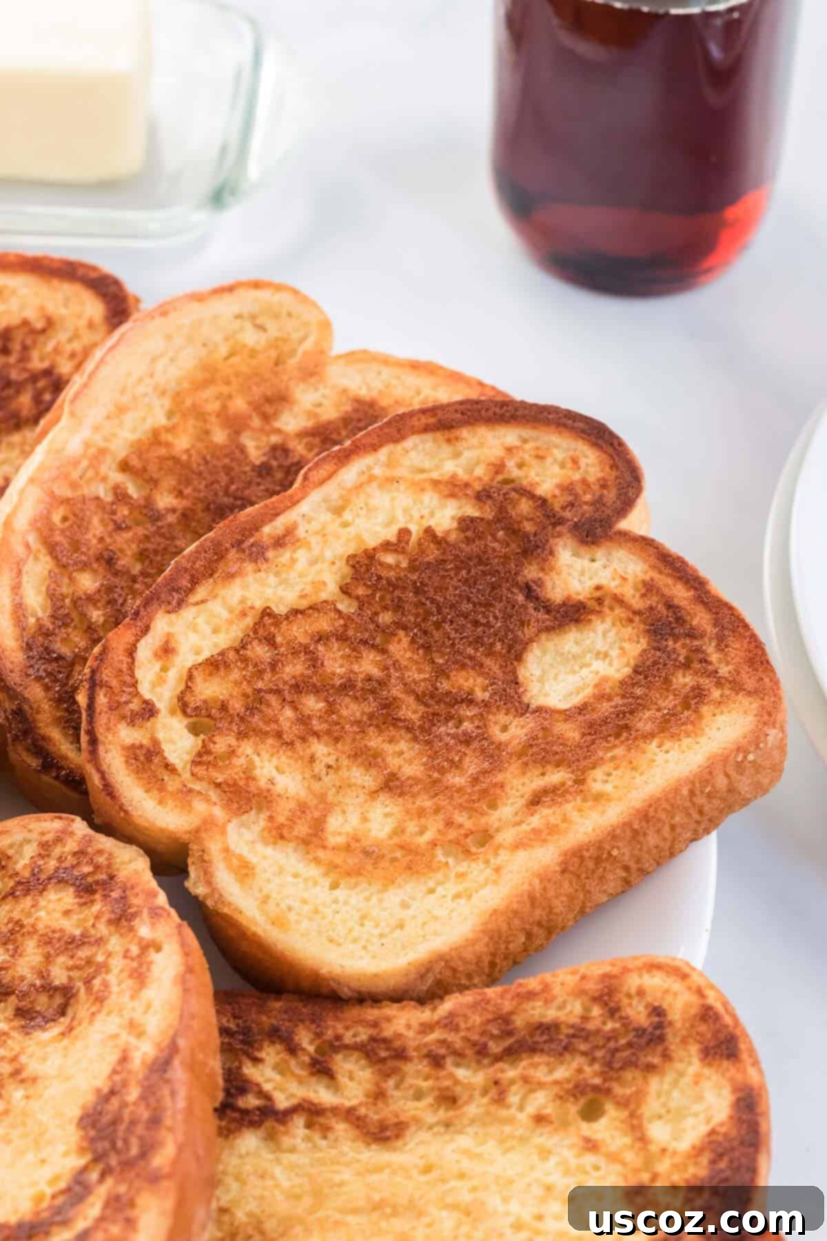 Festive Eggnog French Toast 6 Freshly cooked Eggnog French Toast slices arranged neatly on a white plate, ready for delicious holiday toppings