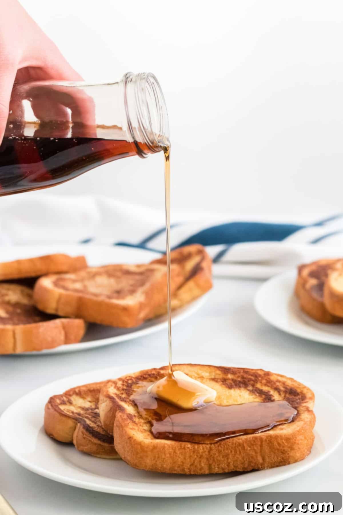 Festive Eggnog French Toast 7 Warm maple syrup being poured generously over a stack of golden brown eggnog French toast slices