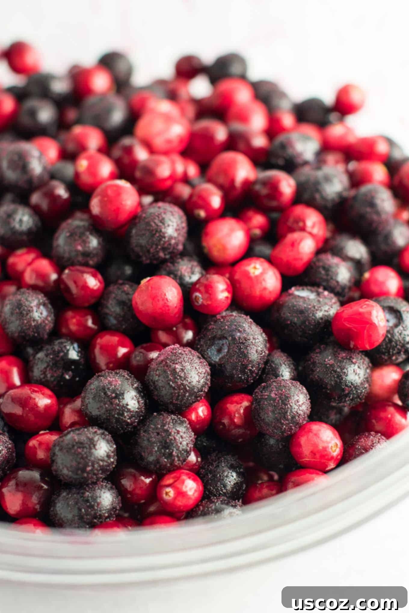 Sweet Tart Cranberry Blueberry Crisp 5 Close-up of frozen blueberries and fresh cranberries mixed in a bowl with sugar and cornstarch, ready for the crisp filling.