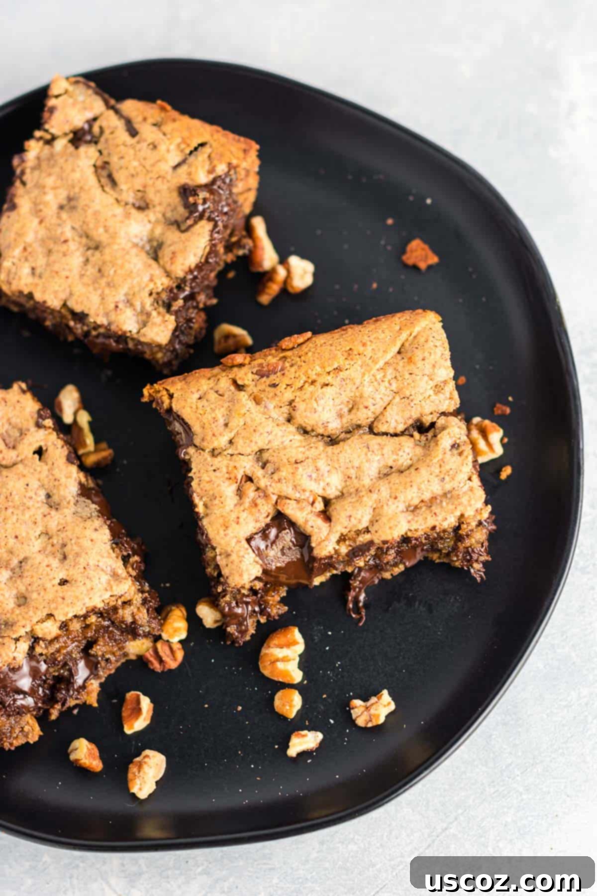 Decadent Dark Chocolate Pecan Cookie Bars 5 Several dark chocolate pecan cookie bars stacked on a plate