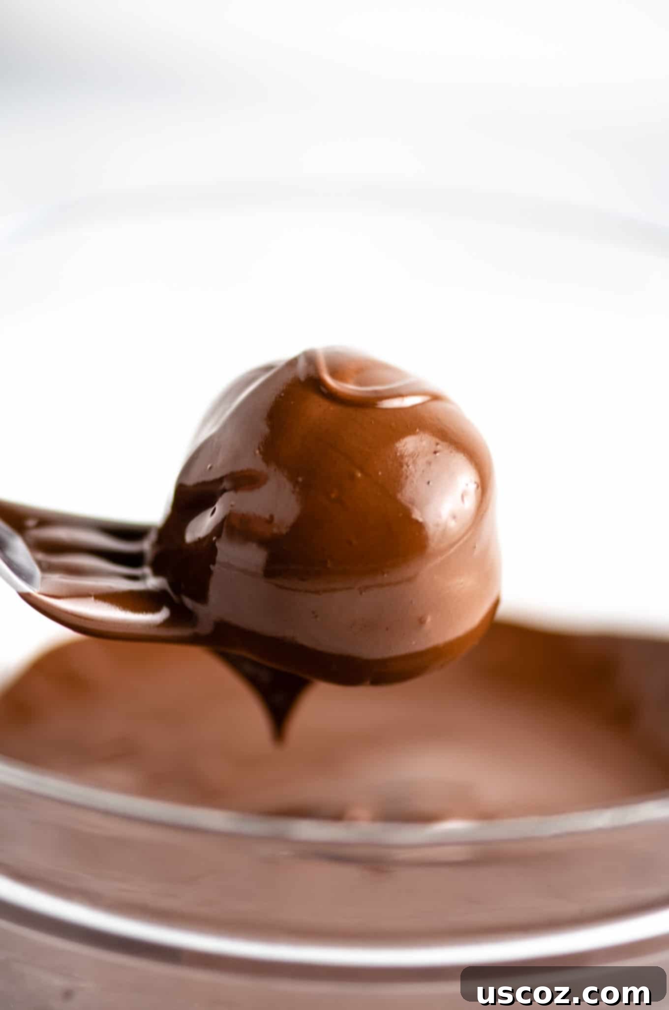 Decadent Yet Healthy No-Bake Peanut Butter Truffles 7 Expertly coated peanut butter truffles drying on a fork after being dipped in chocolate.