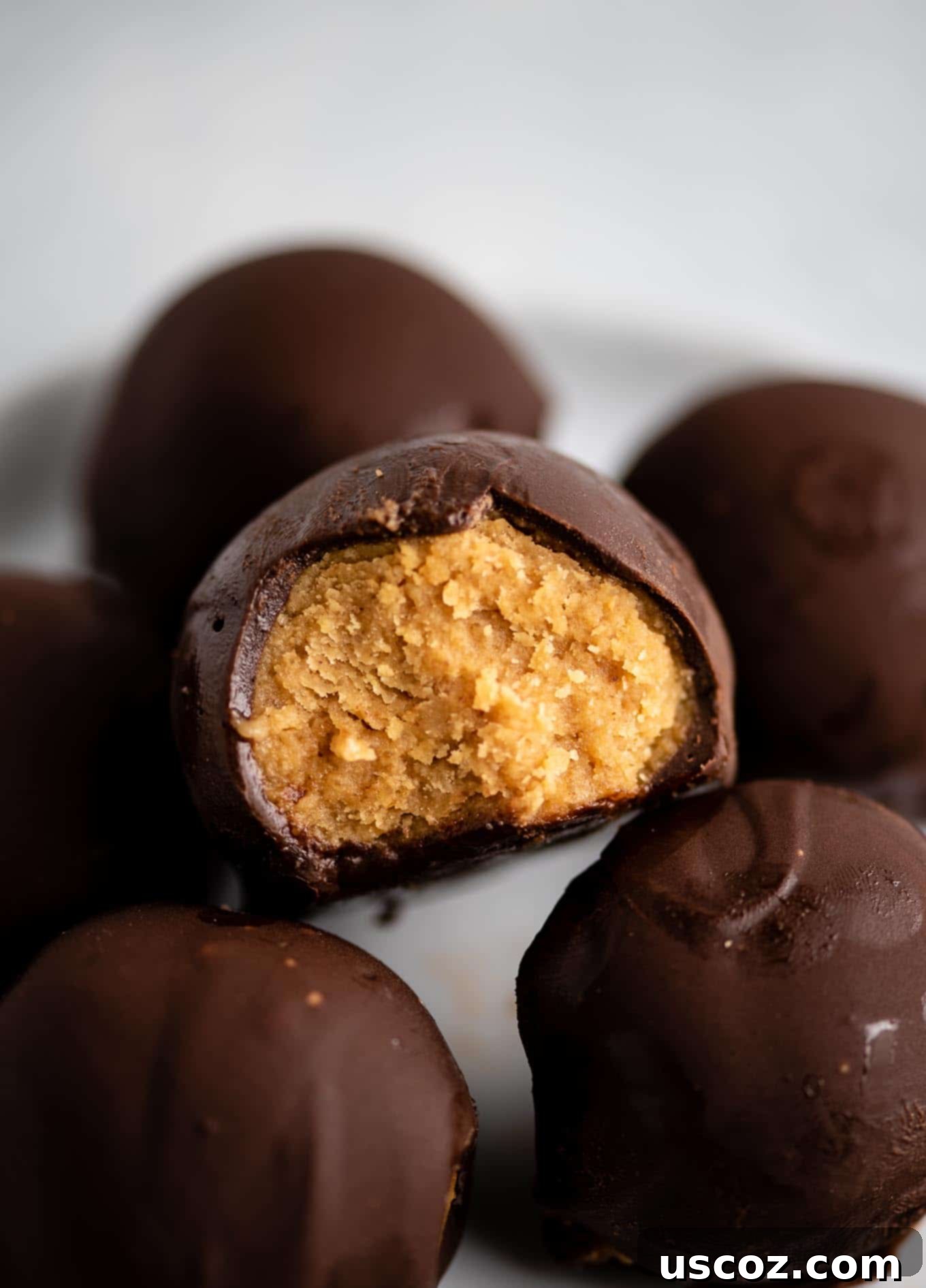 Decadent Yet Healthy No-Bake Peanut Butter Truffles 10 A pyramid stack of finished no-bake peanut butter truffles on a white plate, ready to be served.