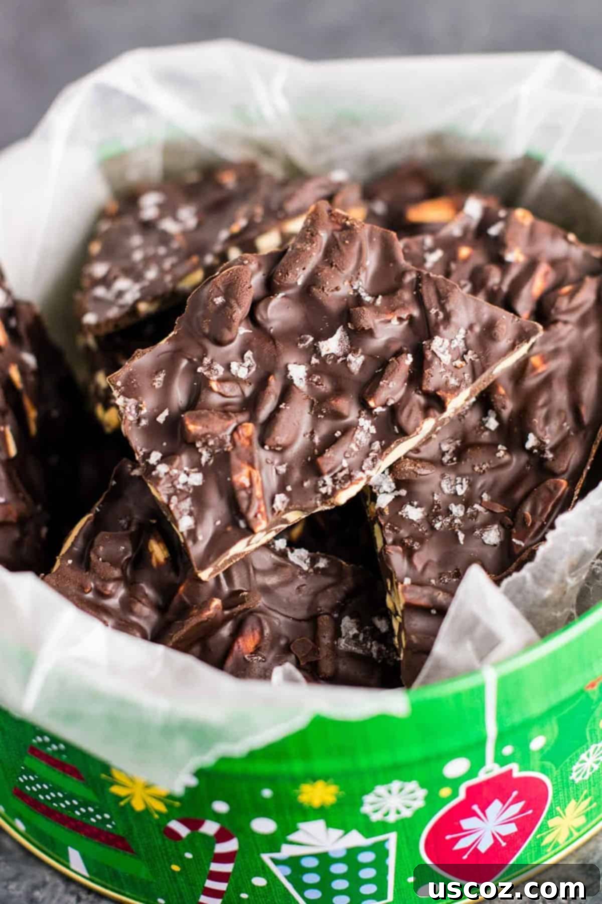 Decadent Dark Chocolate Almond Bark 2 Rich dark chocolate almond bark nestled in a festive Christmas tin, lined with elegant wax paper, ready for holiday gifting or sharing.
