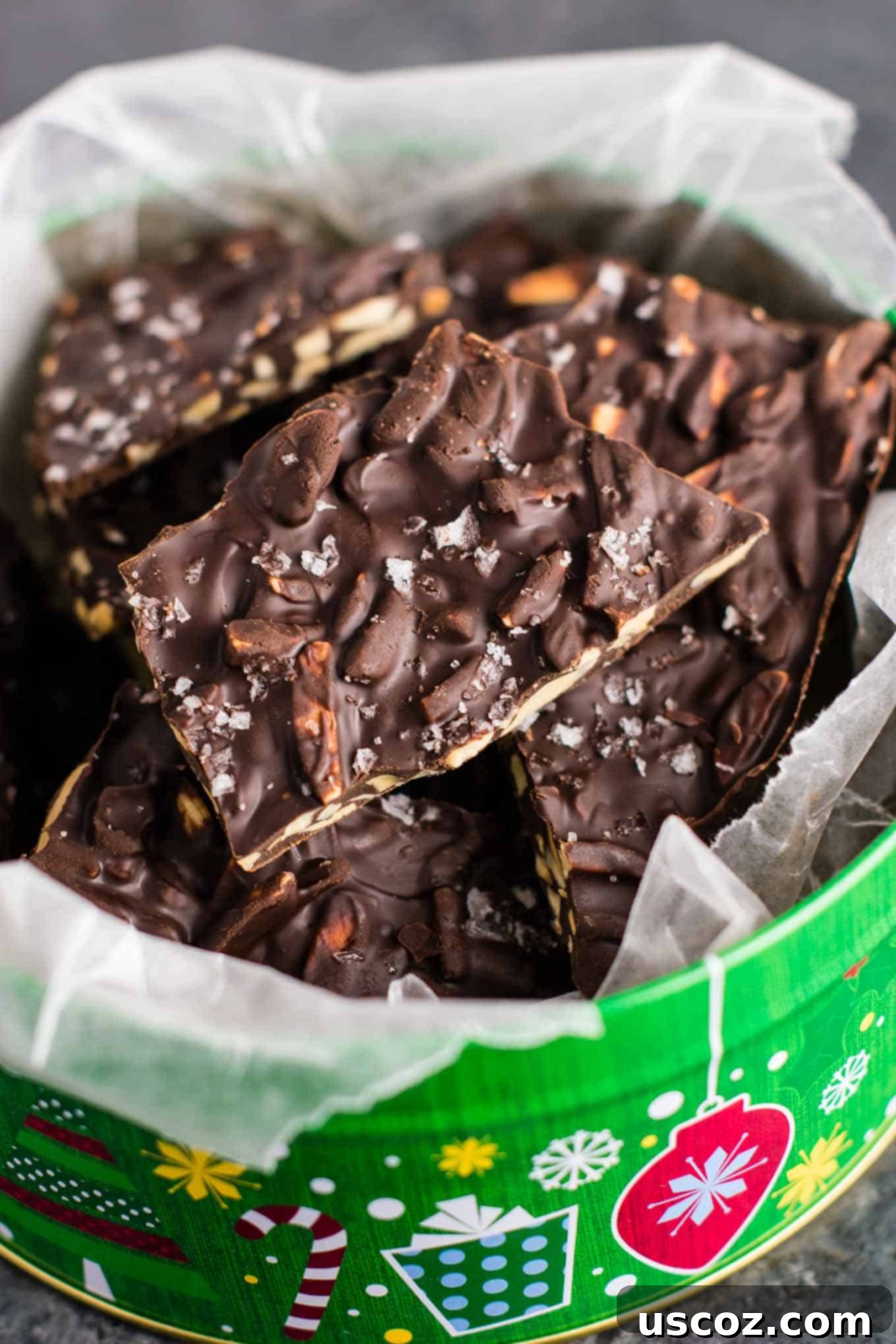 Decadent Dark Chocolate Almond Bark 6 An overhead shot revealing the textured surface of dark chocolate almond bark, artfully arranged in a Christmas tin, sprinkled with sea salt.